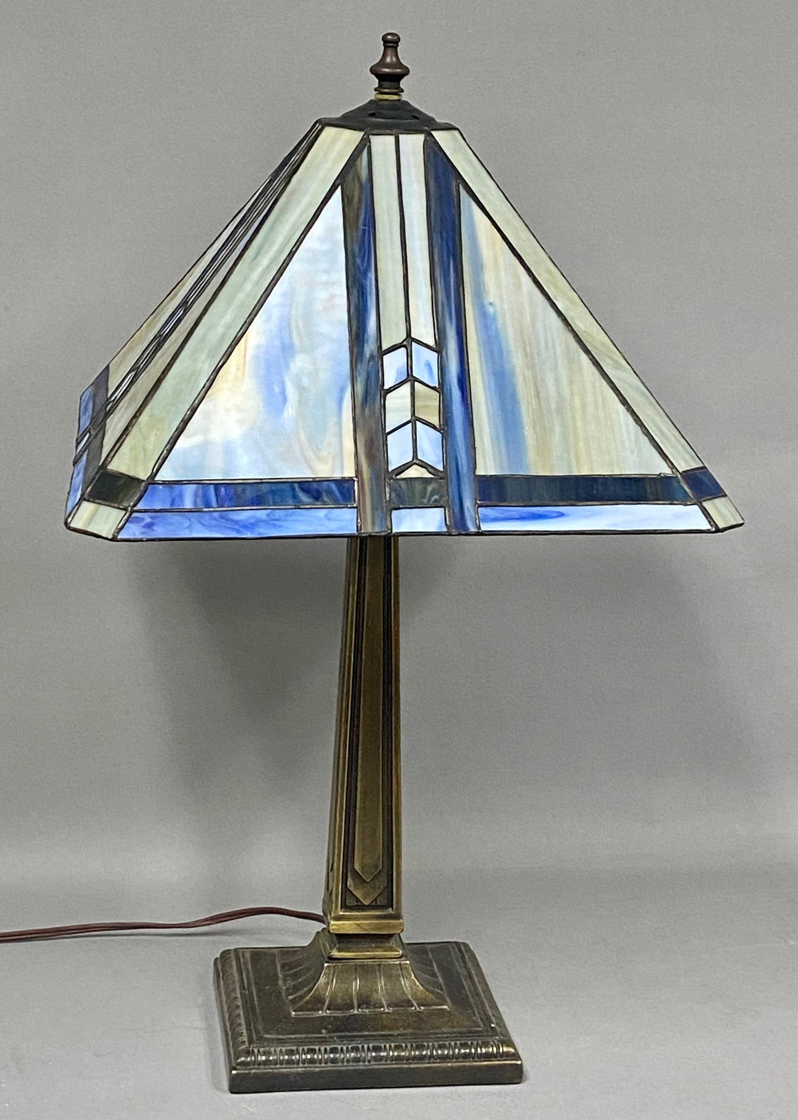 Arts & Crafts Blue Slag Glass Table Lamp: This Arts & Crafts style table lamp features a leaded slag glass shade in a four-sided pyramidal form. The shade is composed of marbleized cream-colored slag glass panels with blue and lavender