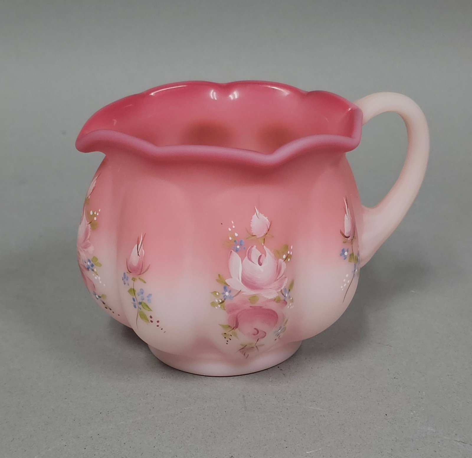 Fenton Rosalene Satin Glass Melon Creamer: This hand-painted Rosalene satin glass creamer by Fenton Art Glass features a melon-ribbed body and a crimped, ruffled rim with a small integral pouring spout. The glass exhibits a characteristic