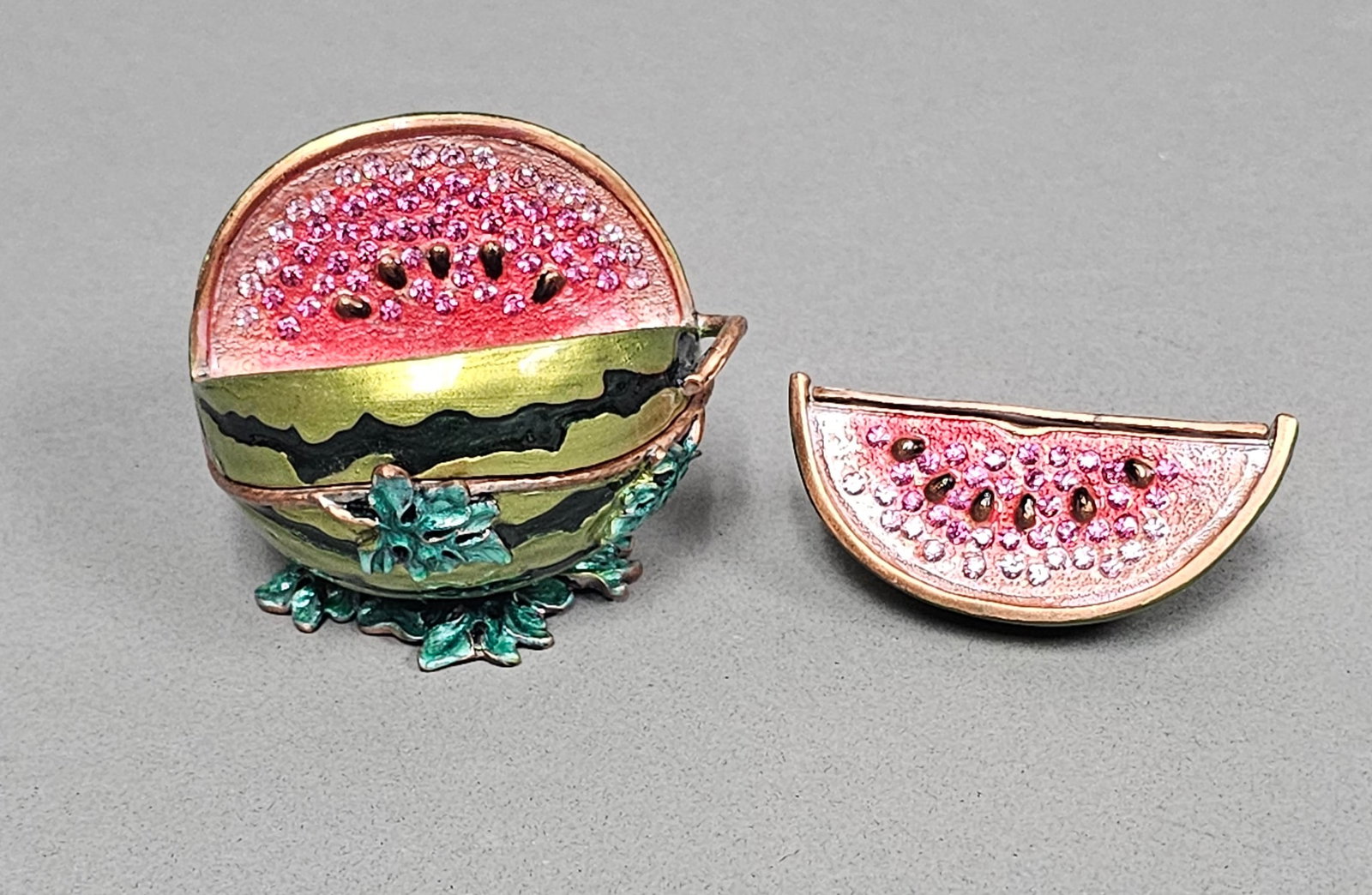 Enameled Metal Jeweled Watermelon Trinket Box: This enameled metal trinket box is fashioned in the form of a whole watermelon. The exterior is finished in lustrous green enamel with textured dark green striping, resting on a base of metallic-highl