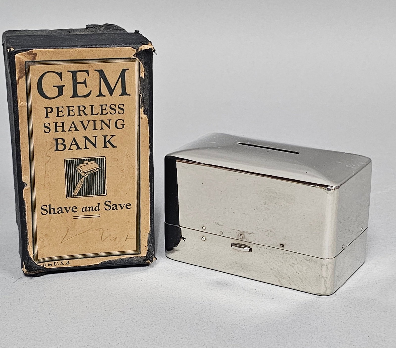Gem Peerless Shaving Bank & Razor: A vintage Gem Peerless Shaving Bank set featuring a chrome-plated metal case designed to serve as both a savings bank for used blades or coins and a travel case for a safety razor. The set includes a 