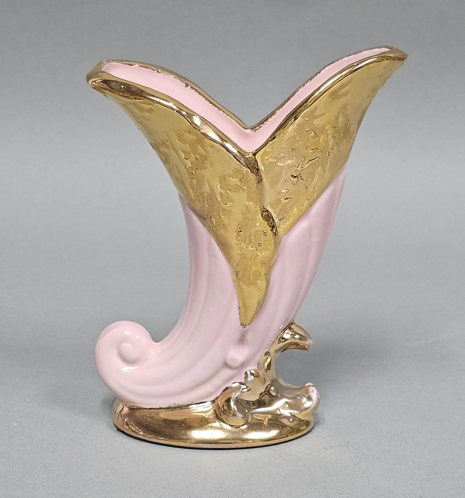 Ceramic Weeping Gold Cornucopia Vase: A mid-century modern ceramic decorative vase in a stylized cornucopia or horn of plenty form. The piece is finished in a two-tone scheme featuring a glossy baby pink glaze on the main body and a textu