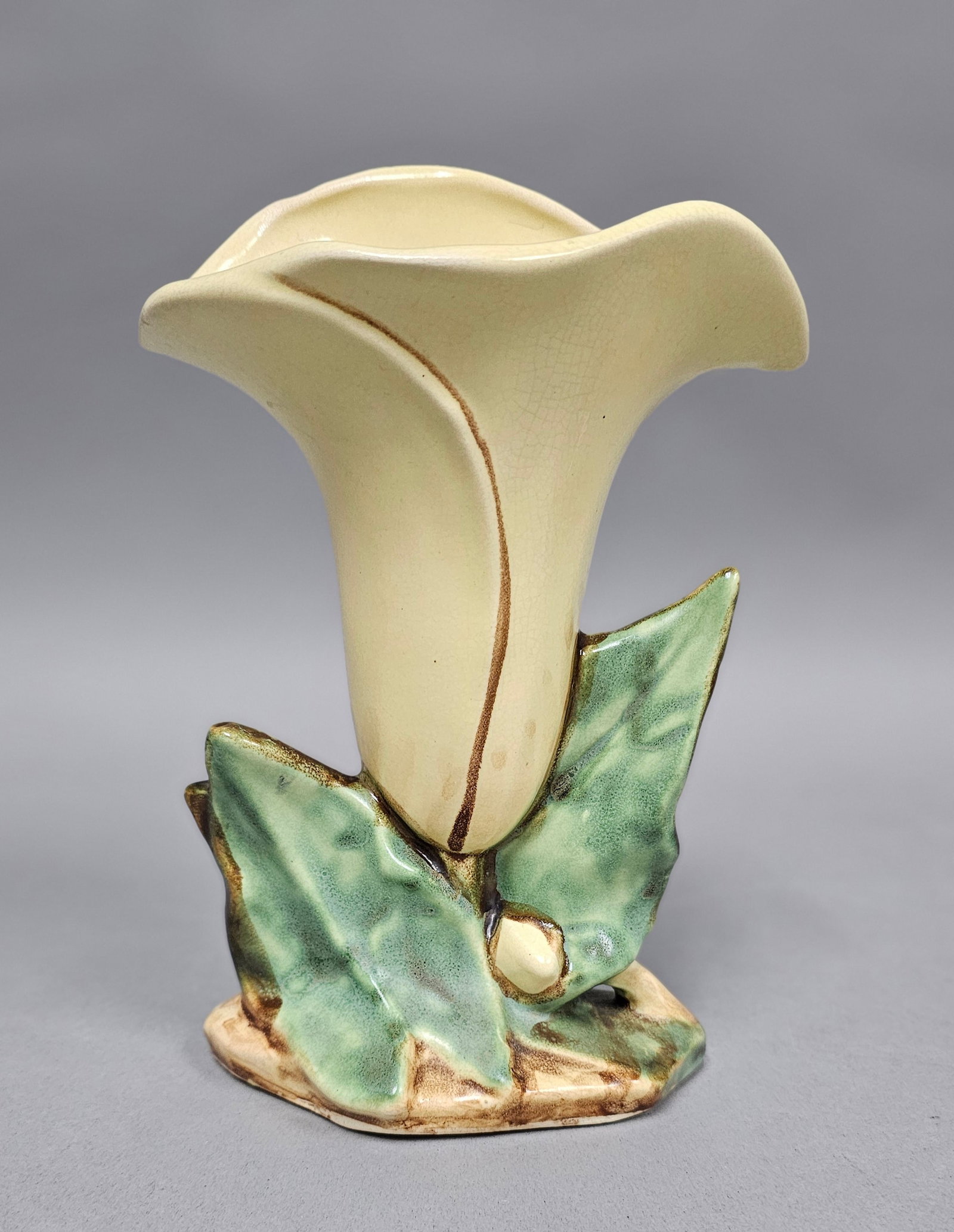 Hull Art Pottery Calla Lily Vase: A mid-century American art pottery vase manufactured by Hull Pottery in the form of a single calla lily. The trumpet-shaped vessel features a flaring rim and is finished in a pale cream to yellow