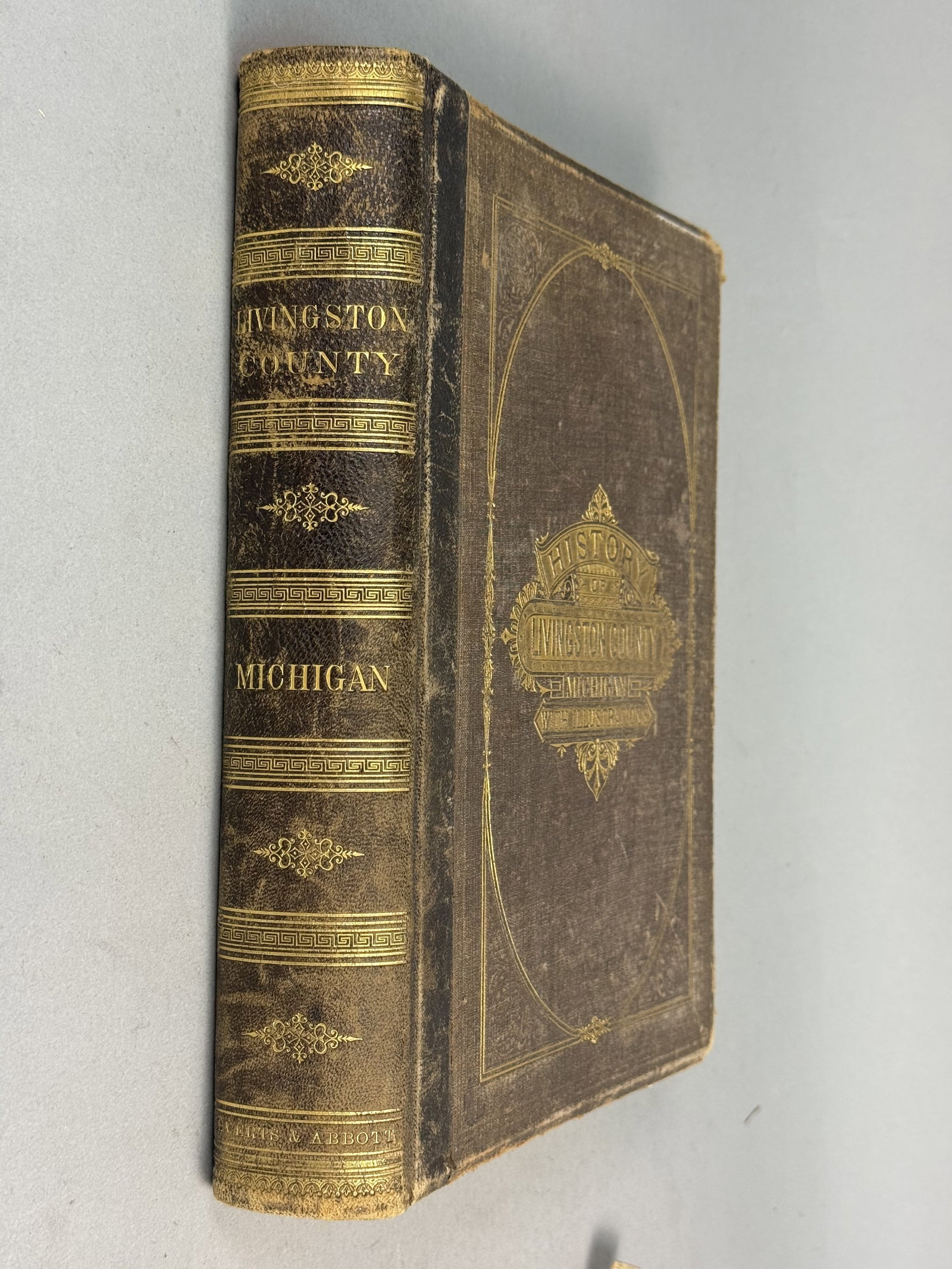 Everts & Abbott Livingston County Michigan History 1880: This quarto-sized regional history is bound in half-leather with textured brown cloth boards featuring gilt-stamped decorative bands and titles. The work is profusely illustrated with lithographic