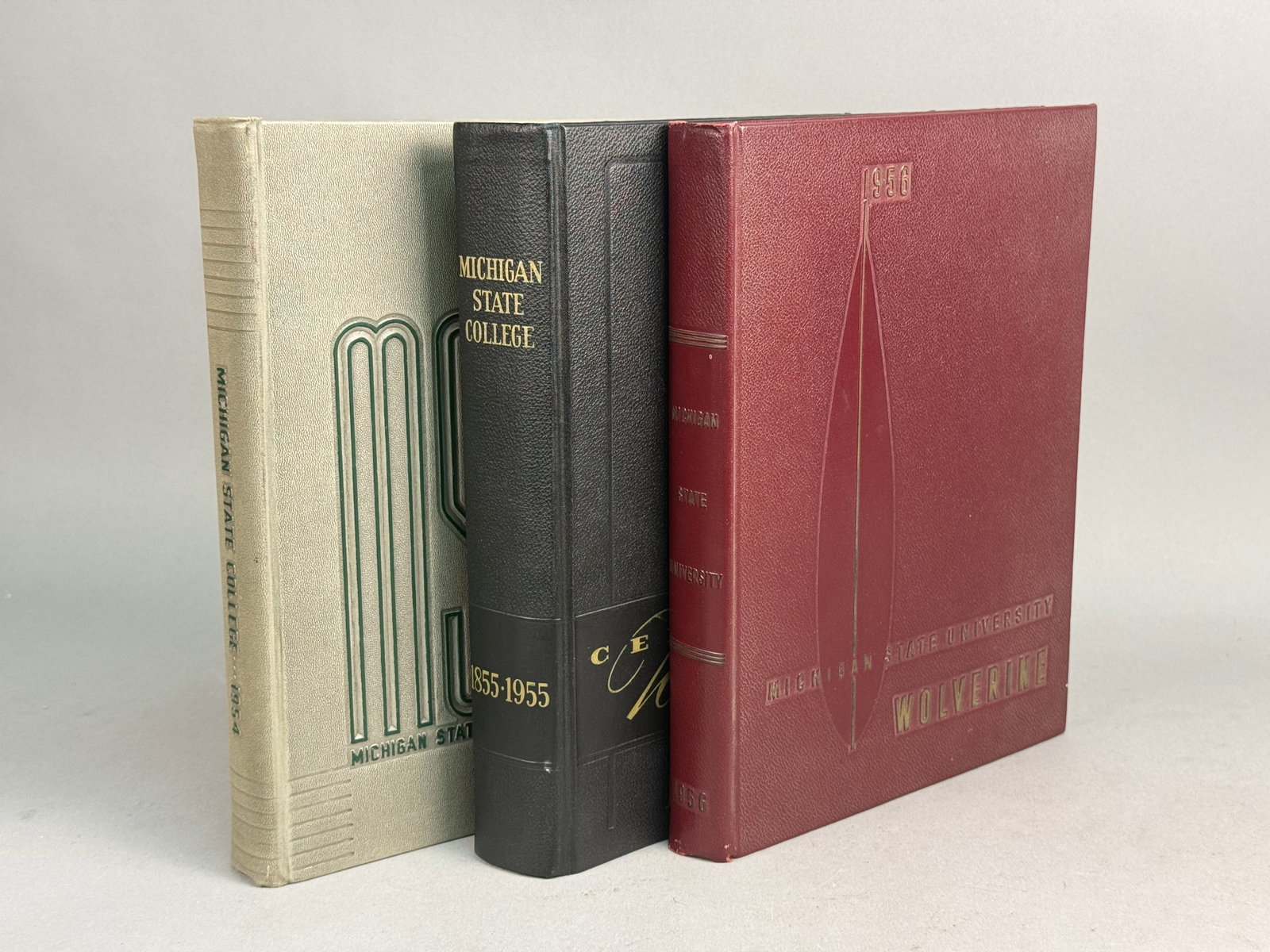 Three Michigan State Wolverine Yearbooks 1954-56: This group features three consecutive editions of the Michigan State Wolverine yearbook for the years 1954, 1955, and 1956. The volumes document the institution's centennial and its official change