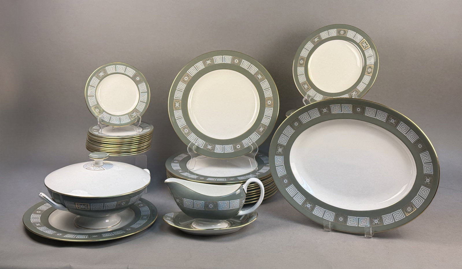 Wedgwood Asia Green China Service: A partial dinner service of Wedgwood bone china in the Asia pattern, featuring a sage green border decorated with a white Greek key meander and circular medallions. The set includes an oval serving pl