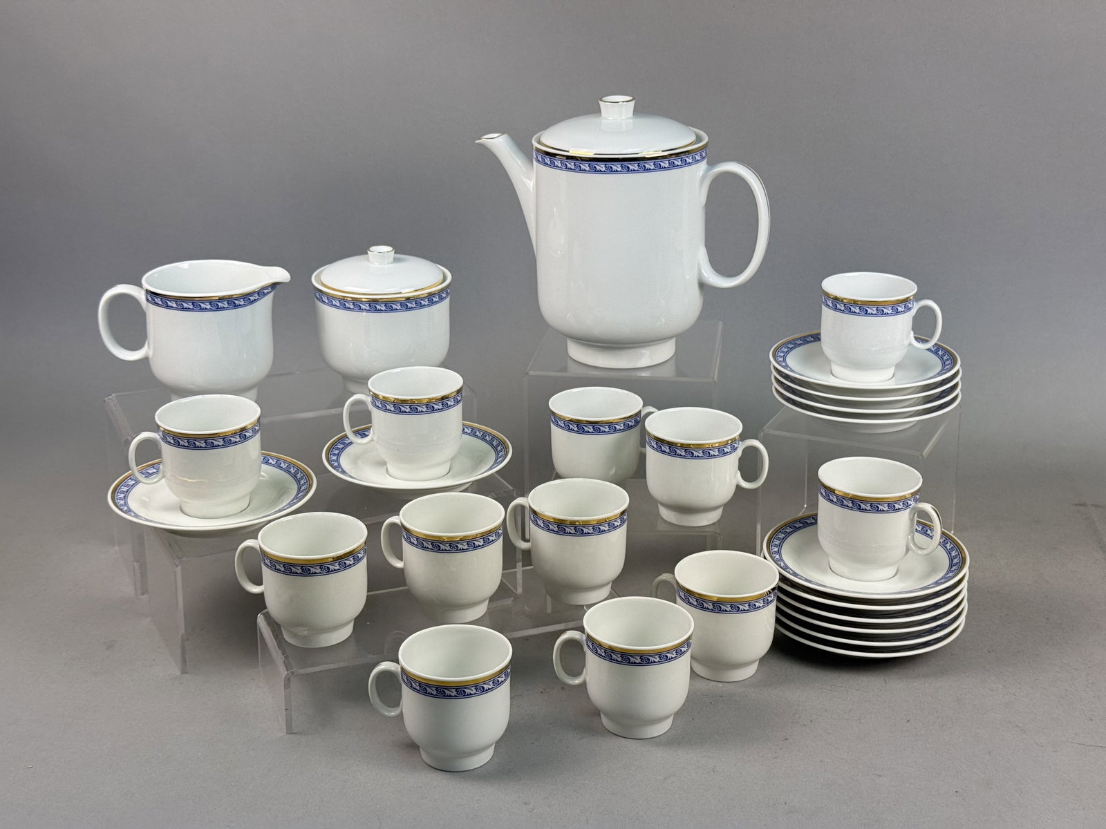 Richard Ginori Porcelain Coffee Service: This Richard Ginori porcelain coffee service features a white ground decorated with a cobalt blue transfer-printed foliate scroll border and gold-gilt trim. The set consists of a coffee pot, a lidded 