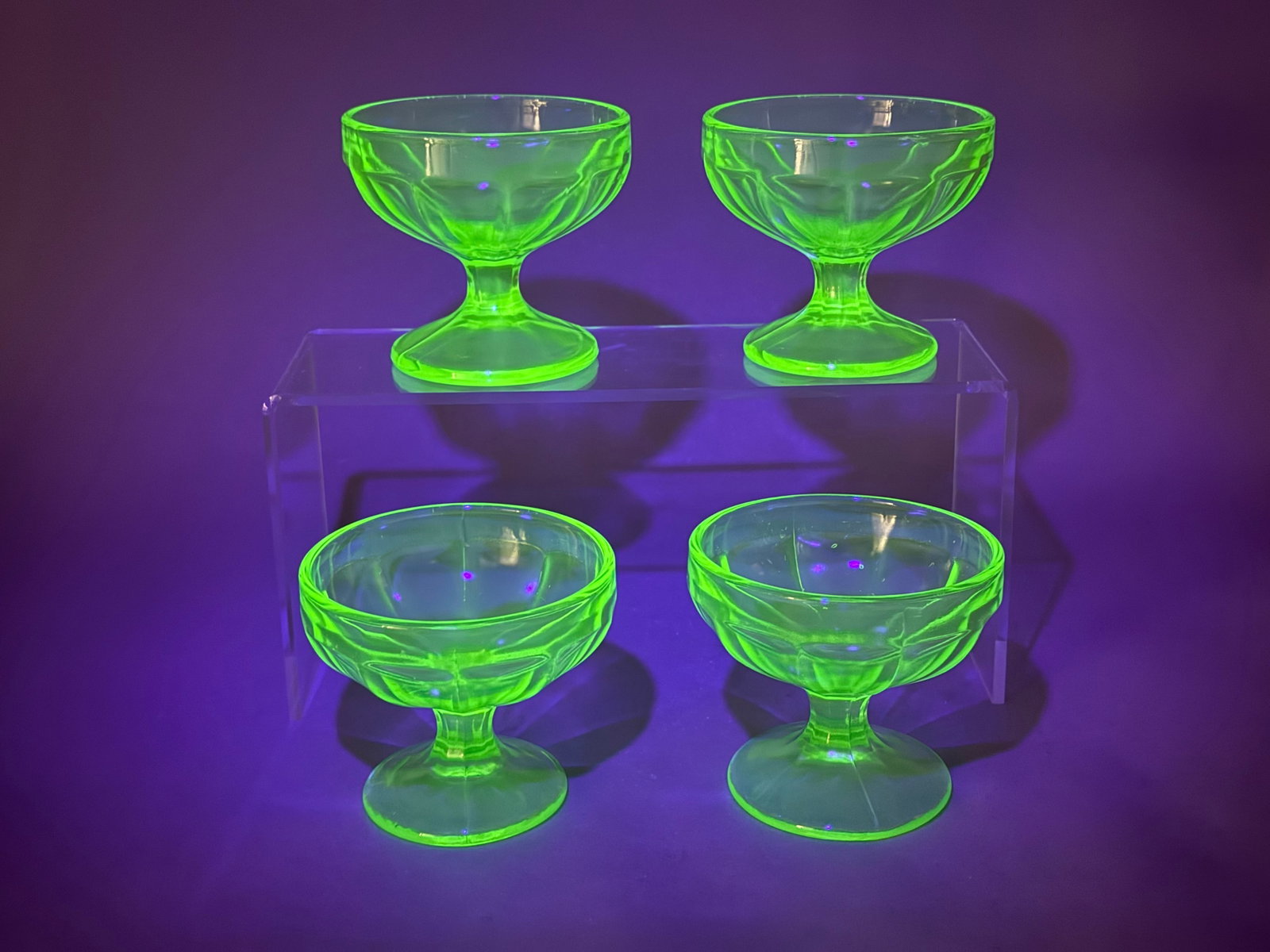 4 Uranium Glass Paneled Sherbet Bowls: A set of four green uranium glass footed sherbet or dessert bowls dating from the Depression era. These transparent light green pressed glass pieces contain a small amount of uranium oxide, which
