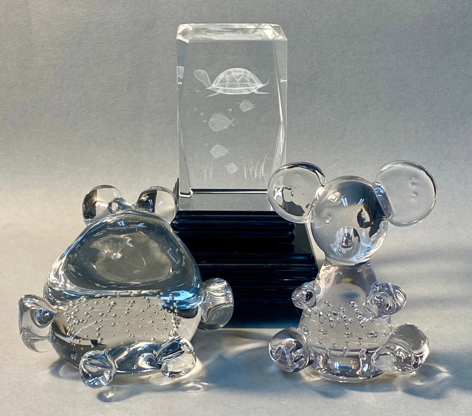 Trio of Decorative Glass Animals: This lot comprises a rectangular laser-etched crystal block and two glass animal figurines. The crystal block features a three-dimensional underwater scene and includes an illuminated tiered black