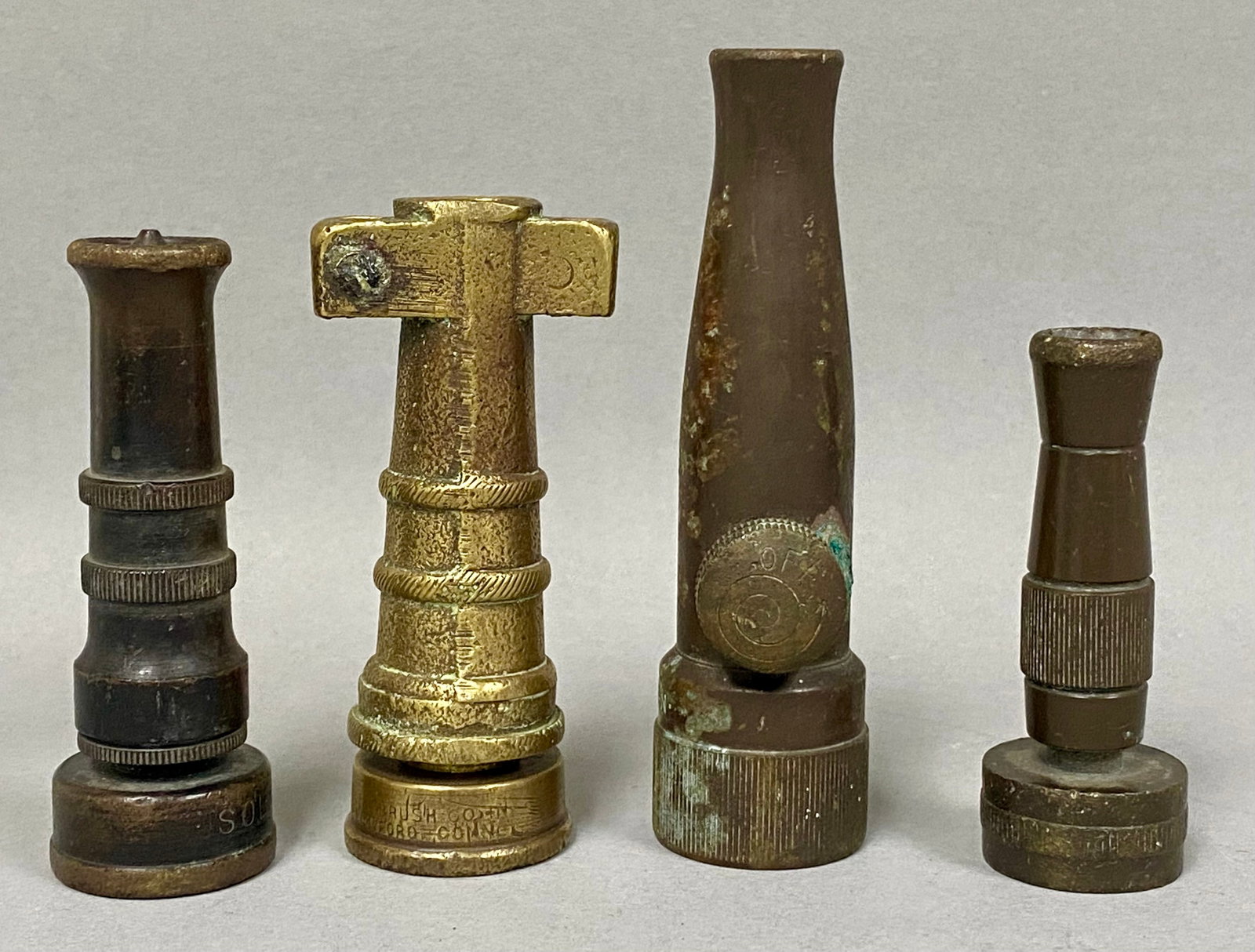 Four Vintage Brass Garden Hose Nozzles: A set of four vintage solid brass garden hose nozzles including a T-shaped specialty model marked for the Fuller Brush Company of Hartford, Connecticut, and a side-valve nozzle marked Craftsman. One