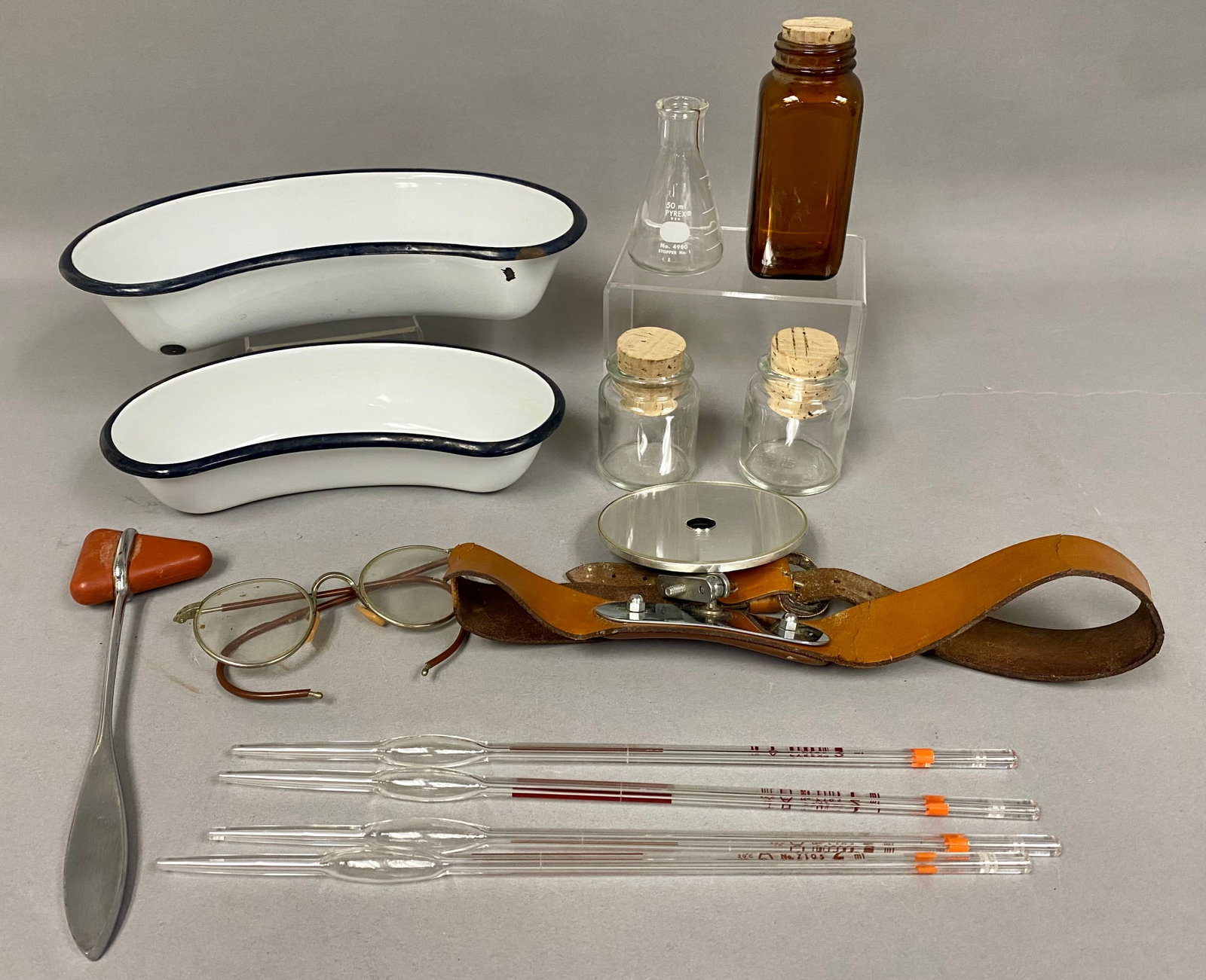 Collection of Vintage Medical and Laboratory Equipment: This group features laboratory glassware marked by Pyrex, including a 50ml Erlenmeyer flask and four 2ml pipettes. Diagnostic tools include a Bausch & Lomb head mirror with a boilable backing on a
