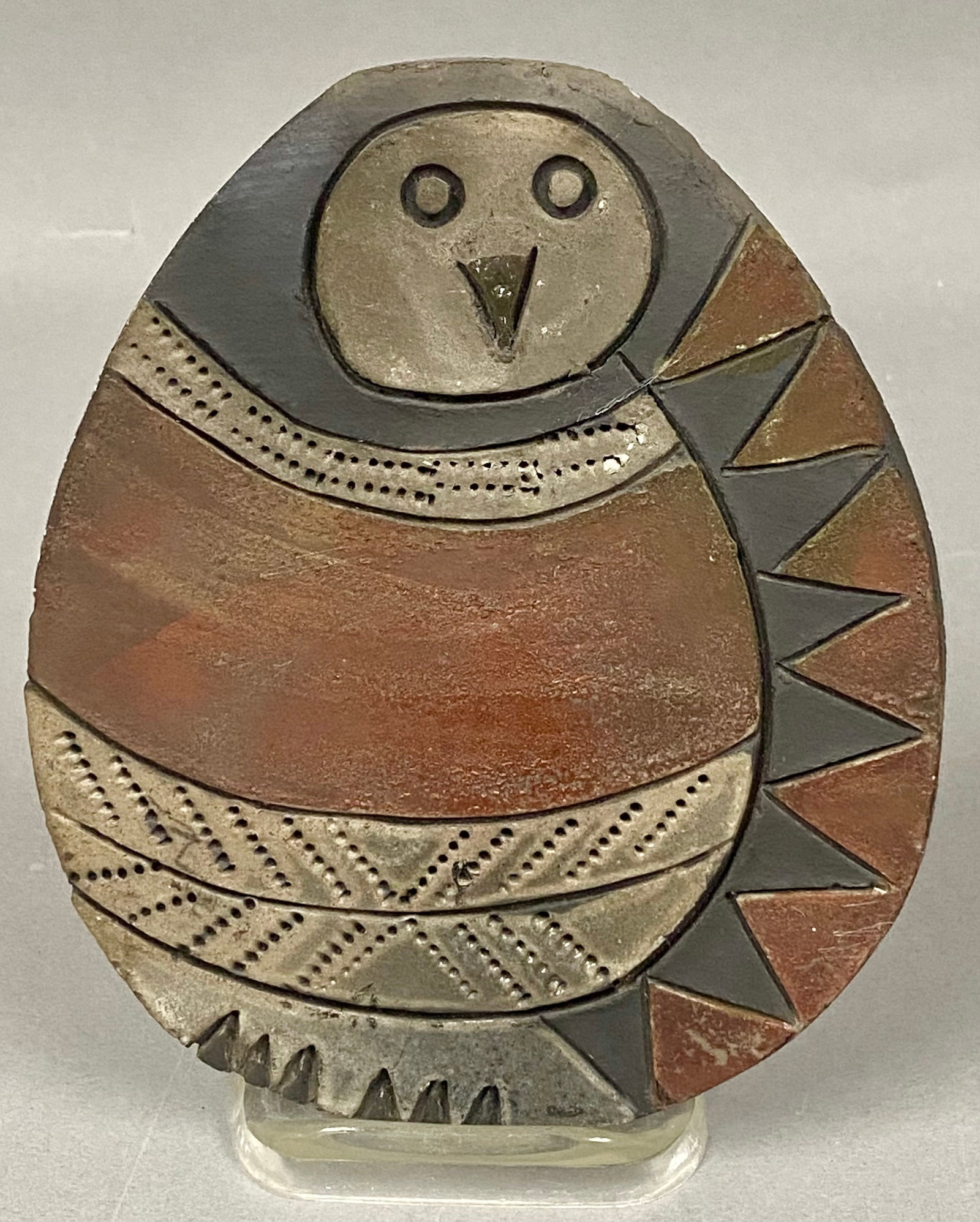 Jordy Studio Pottery Owl Plaque: This ovid studio pottery wall plaque is by the workshop of Einar and Bess Jordy. The stoneware body is decorated with iron-red, charcoal, and grey tones, featuring rows of impressed stippling and a