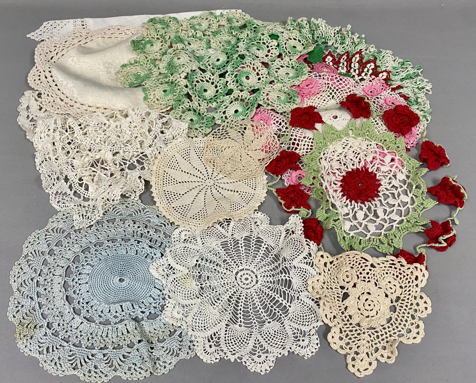 A Collection of Vintage Crocheted Doilies: An assortment of approximately 15 hand-crocheted textiles featuring a variety of traditional patterns, including white-on-white lace and ornate three-dimensional floral designs. The lot includes linen