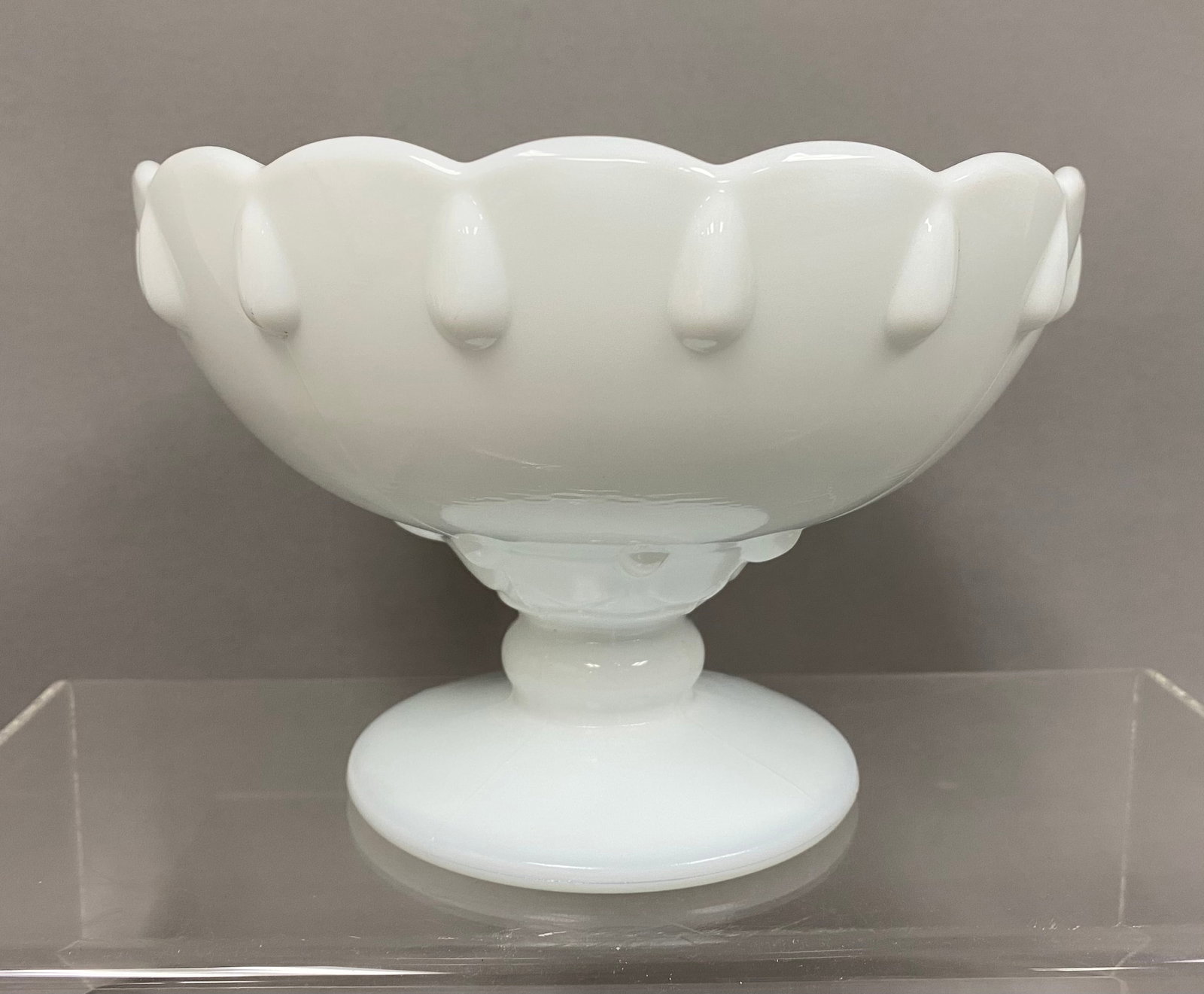 Indiana Glass Teardrop Pedestal Bowl: This Indiana Glass Company milk glass pedestal bowl is featured in the Teardrop pattern. The opaque white body is decorated with a row of raised teardrop bosses below a scalloped rim. It is supported