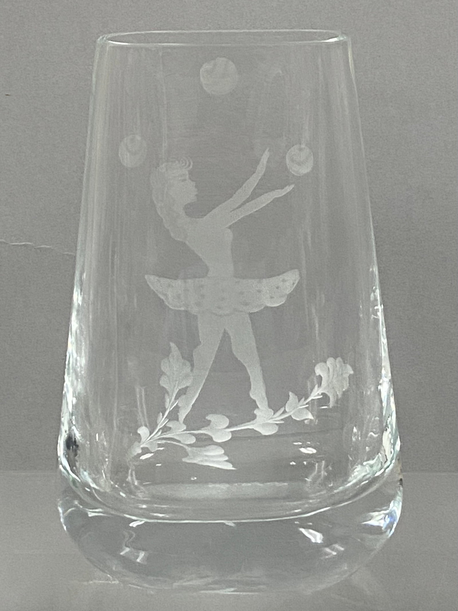 Kosta Engraved Crystal Ballerina Vase: This Kosta crystal vase, model 76-44, features a wheel-engraved motif of a ballerina juggling three spheres while standing on a trailing leafy vine. The tapered rectangular vessel is constructed with