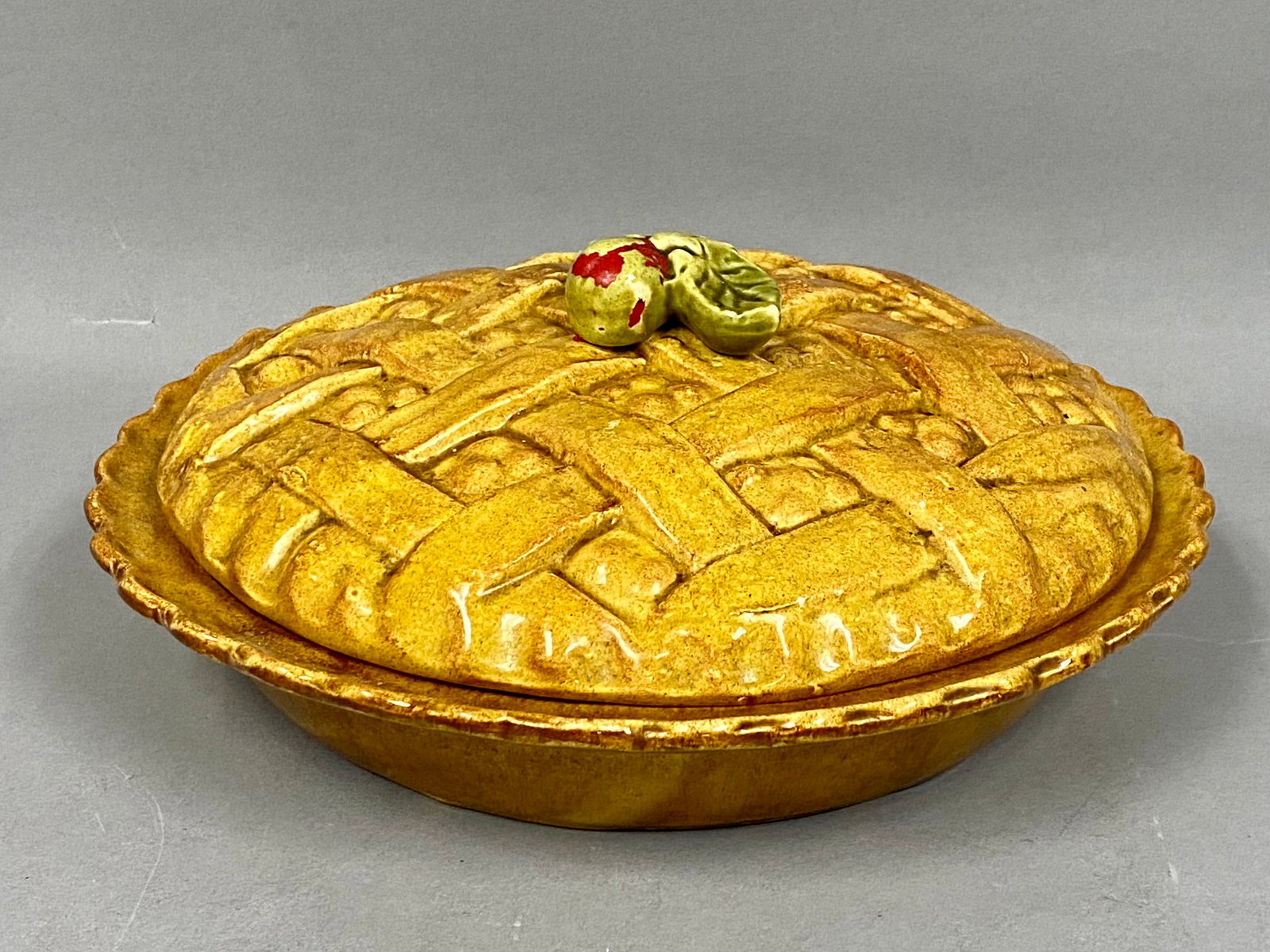 NAC Ceramic Lattice Pie Dish: A two-piece glazed earthenware pie dish and lid set marked NAC. The domed lid is molded with a lattice-crust pattern and a hand-decorated fruit finial. The set features a mottled mustard-yellow glaze