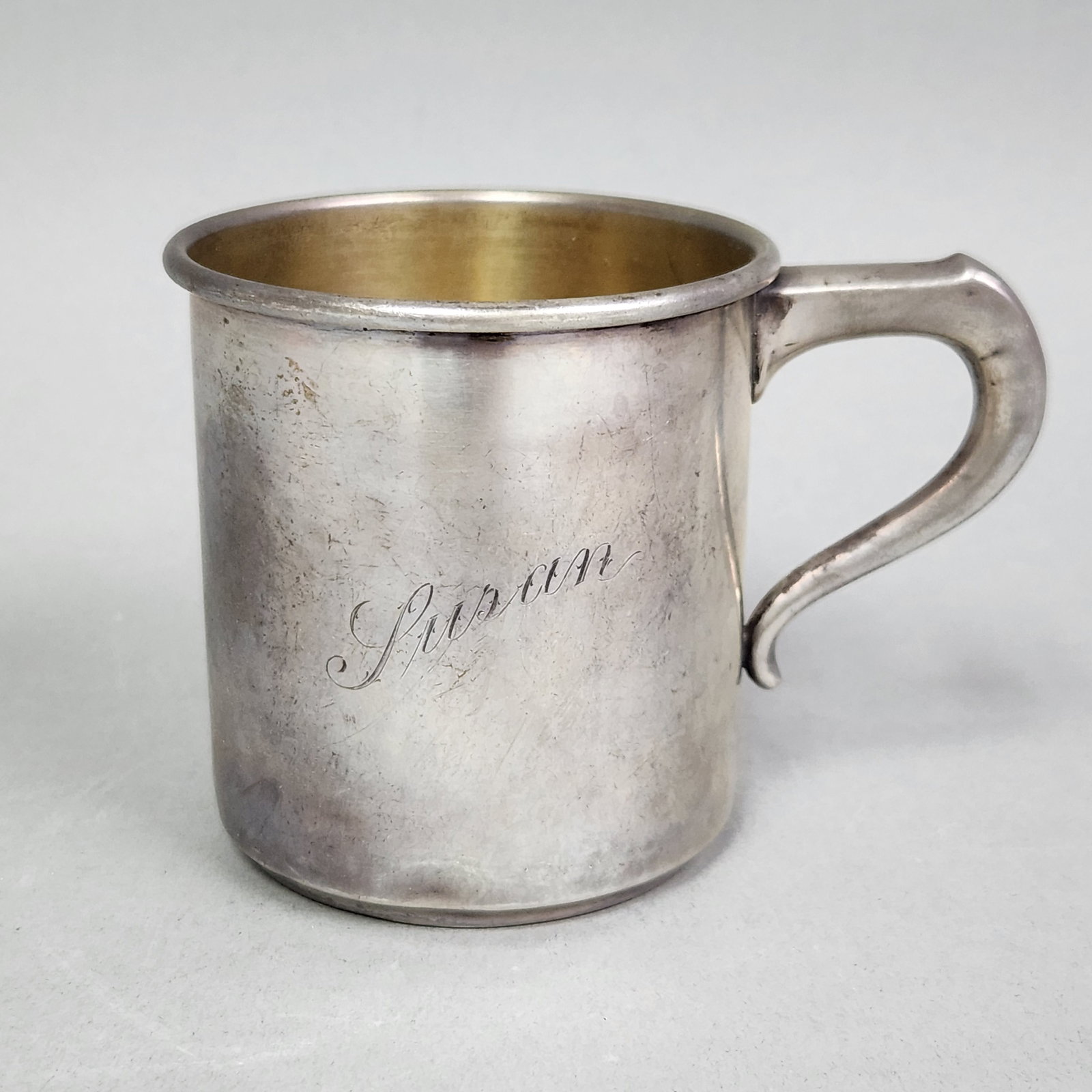 International Sterling Child's Cup 84.95 Grams: This monogrammed sterling silver child's cup by International Silver features a tapered cylindrical form with a gold-washed interior. The base is stamped with the knight's head logo for Simpson, Hall,