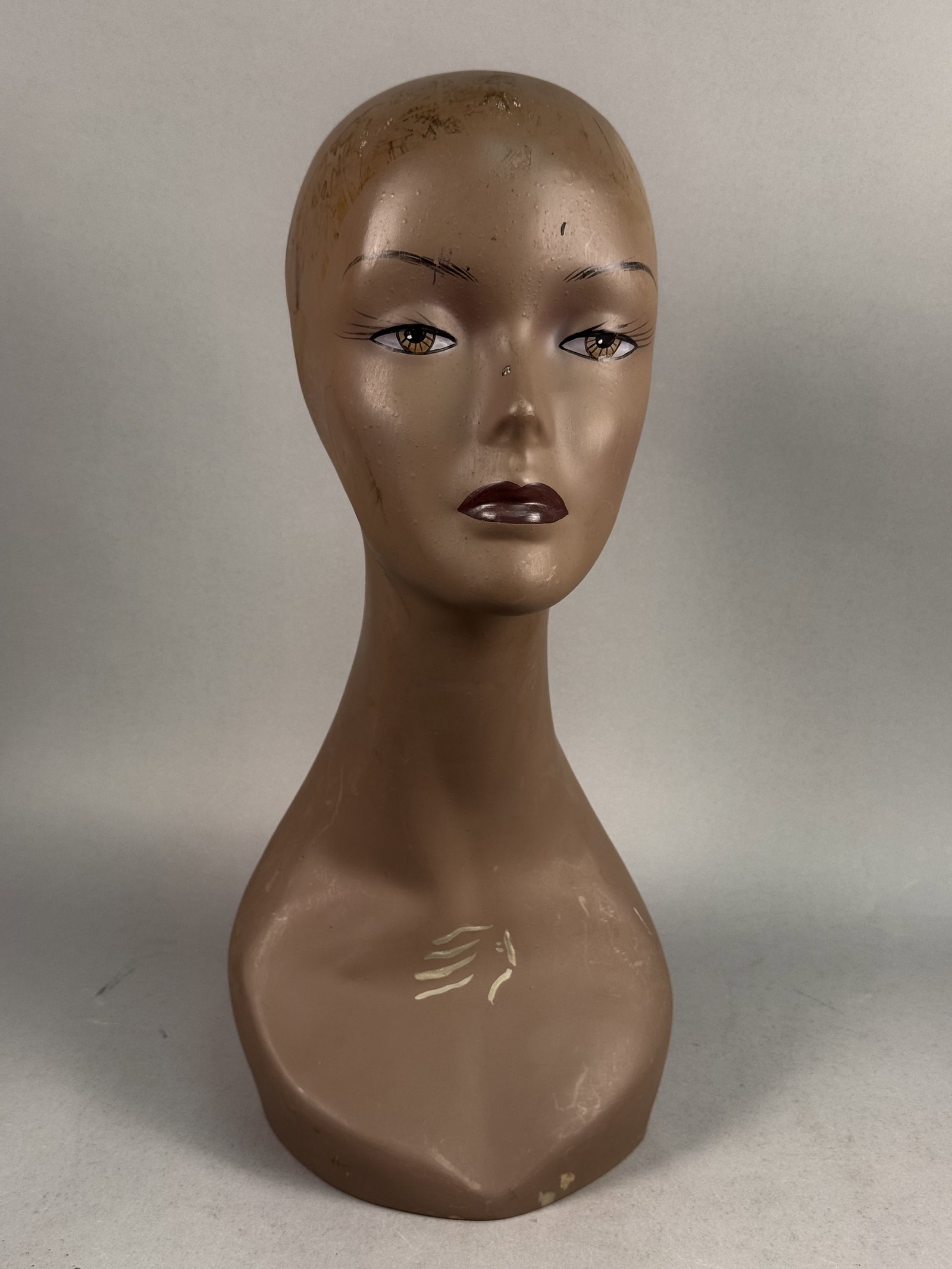 Painted Composition Elongated Mannequin Head: This vintage millinery or wig mannequin head is designed in a stylized mid-century female form featuring a long, slender neck and partial bust. The piece is finished in a tan-brown paint with hand-pai