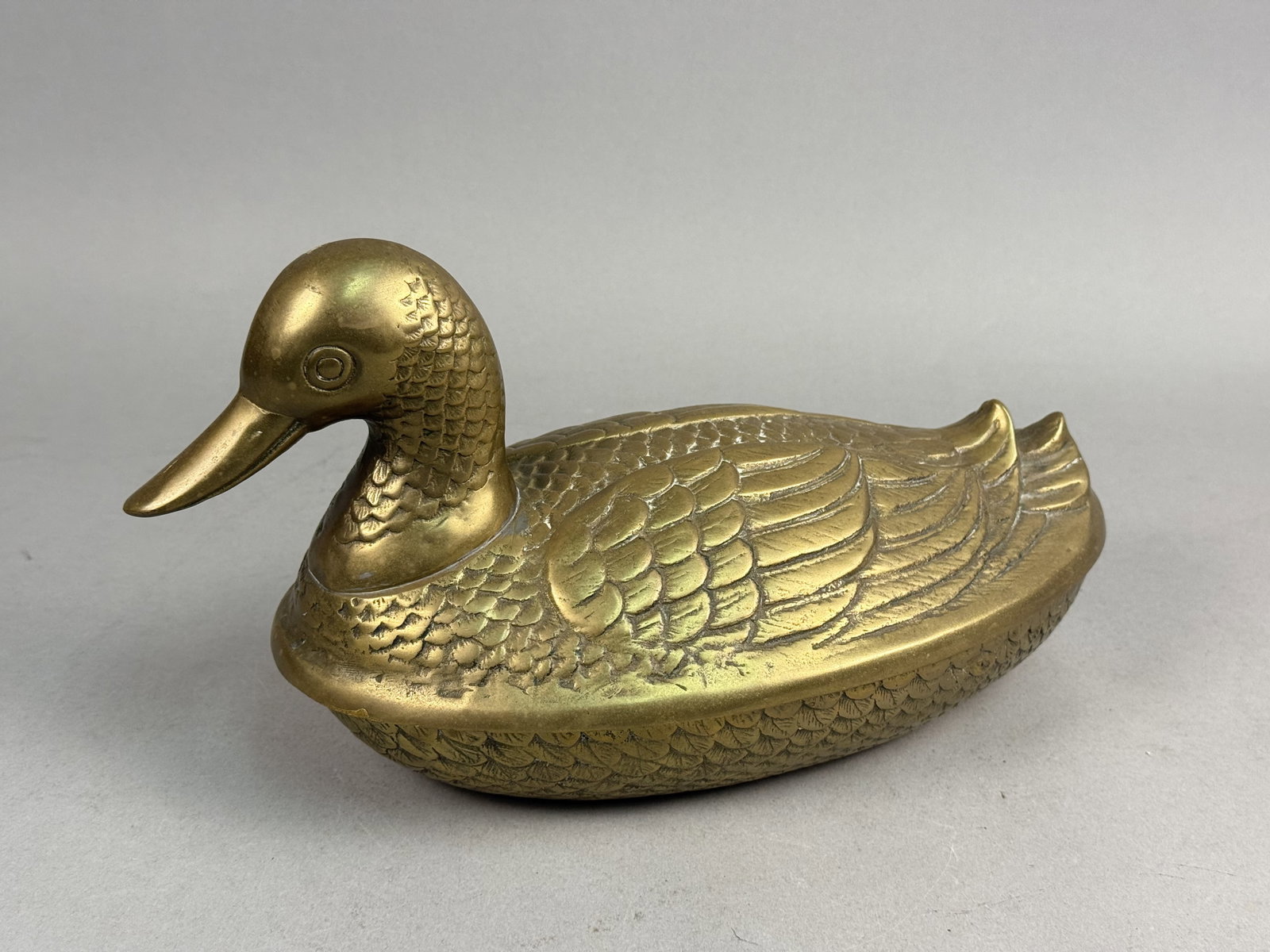 Korean Brass Lidded Duck Box: A vintage cast solid brass lidded container fashioned in the form of a swimming duck. The piece consists of two cast sections that fit together at a horizontal seam along the midpoint of the body. The