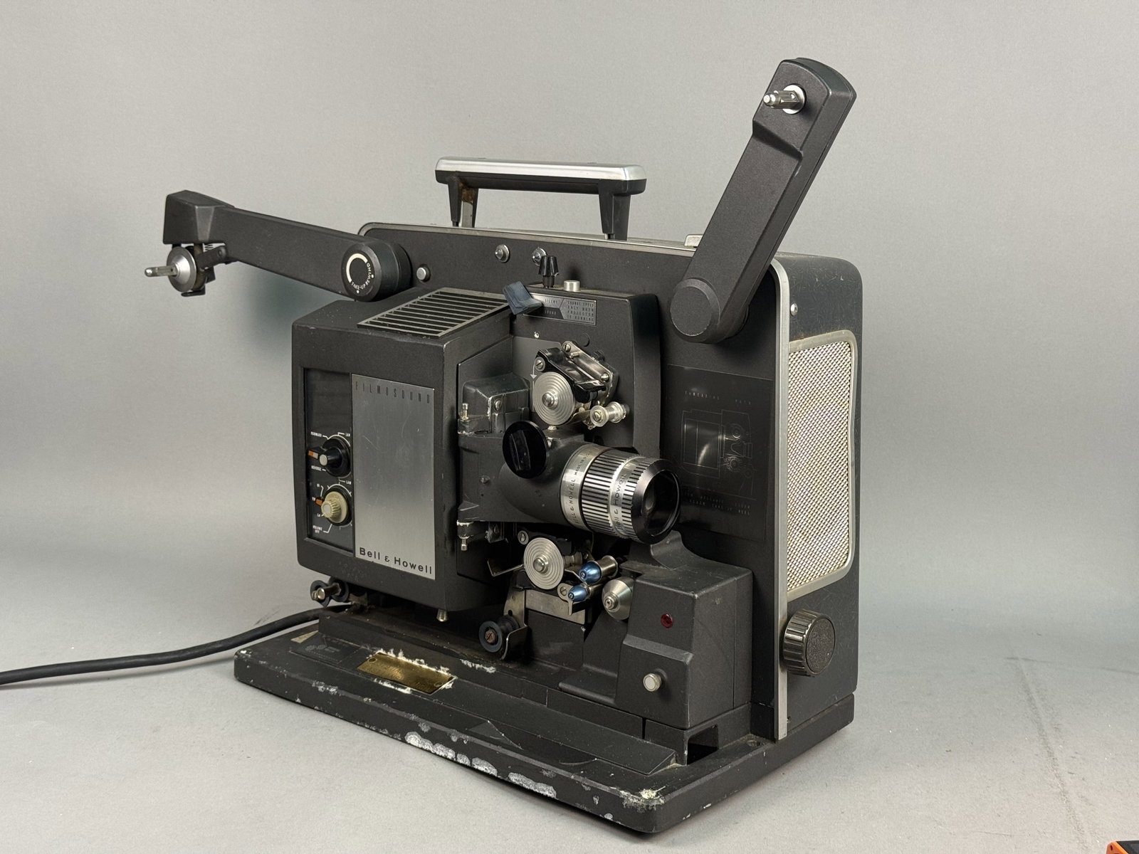 Bell & Howell Filmosound 535 16mm Projector: A vintage Bell & Howell Filmosound model 535 16mm sound film projector. The unit features a textured black metal and composite housing with a built-in speaker behind a silver-tone mesh grille and