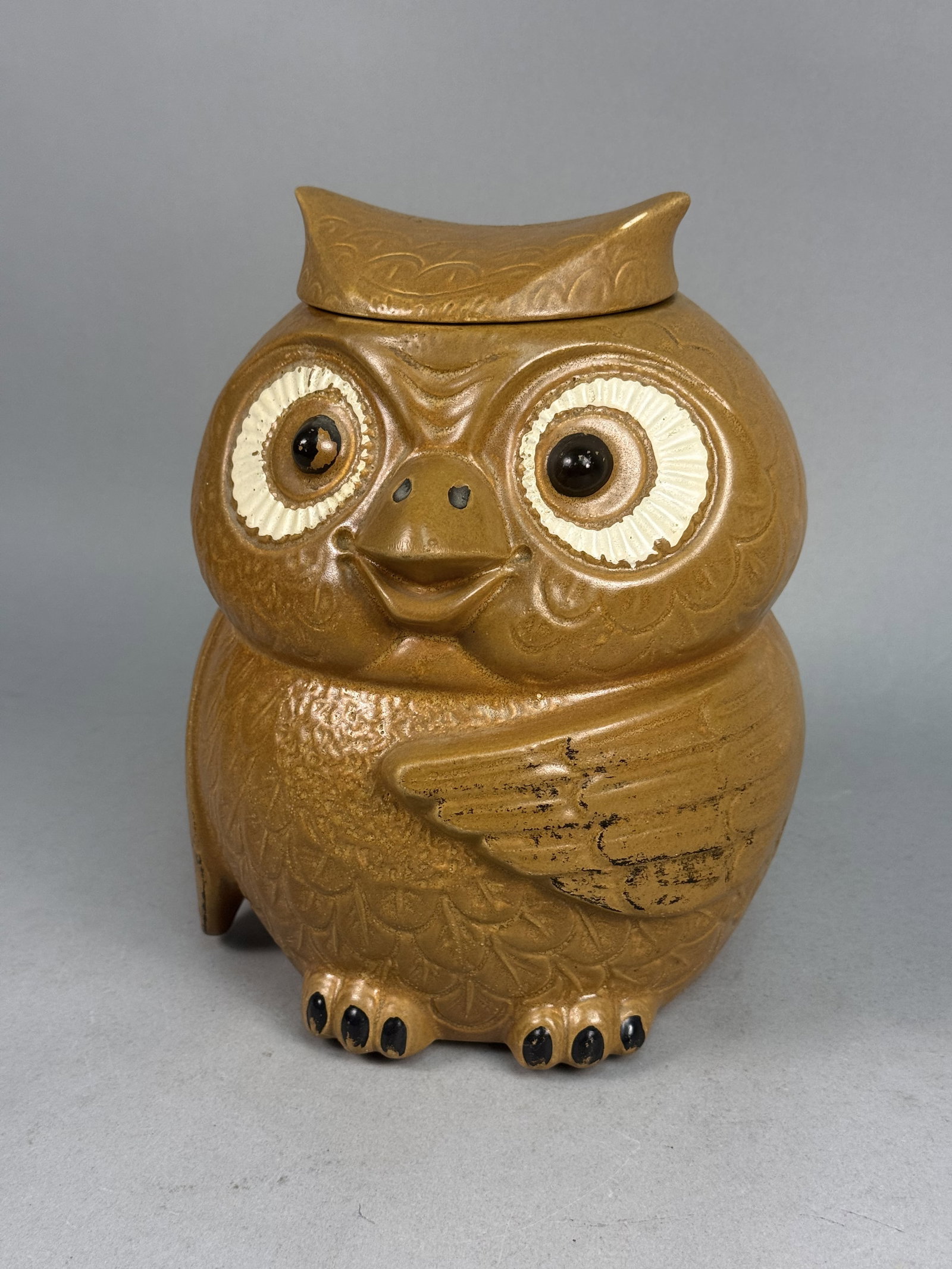 McCoy Earthenware Brown Owl Cookie Jar: This American figural earthenware cookie jar is shaped as a stylized owl, produced by the Nelson McCoy Pottery Company. The two-piece vessel features a mottled brown matte glaze over a molded body wit