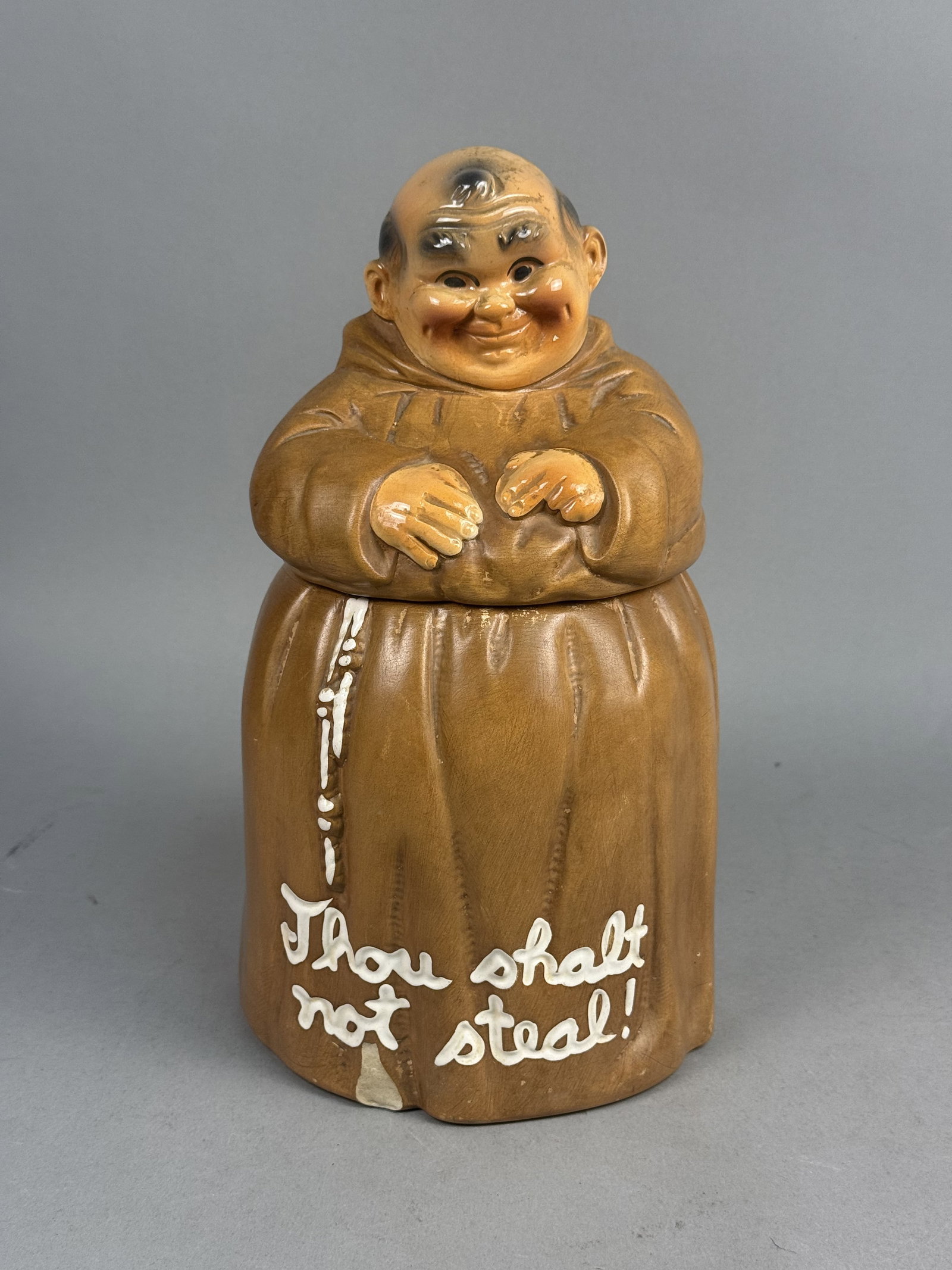 Glazed Earthenware Jovial Monk Cookie Jar: A vintage two-piece glazed earthenware novelty cookie jar modeled in the form of a rotund, jovial monk. The hand-painted figure features expressive facial details including rosy cheeks and a wide
