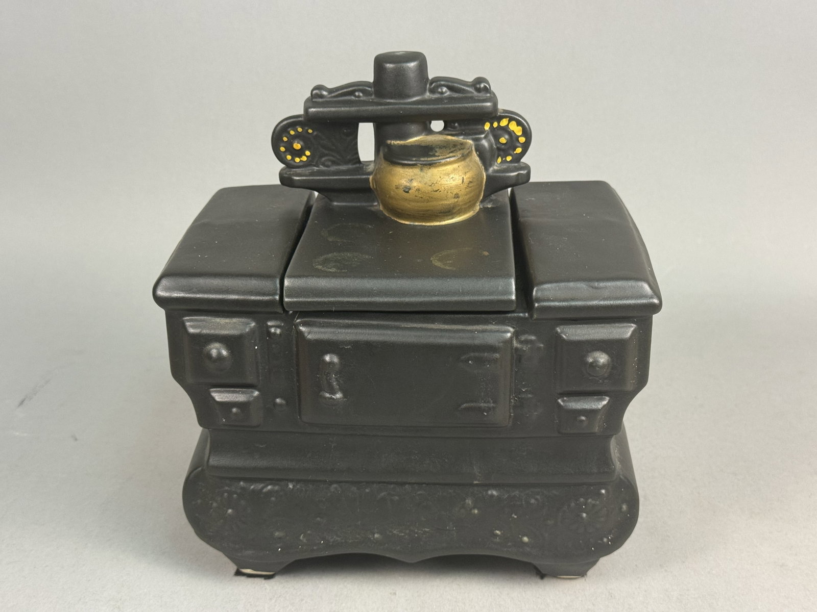 McCoy Ceramic Cookstove Cookie Jar: A vintage ceramic novelty cookie jar produced in the form of a miniature wood-burning or coal kitchen cookstove. The earthenware piece is finished in a matte black glaze intended to simulate the