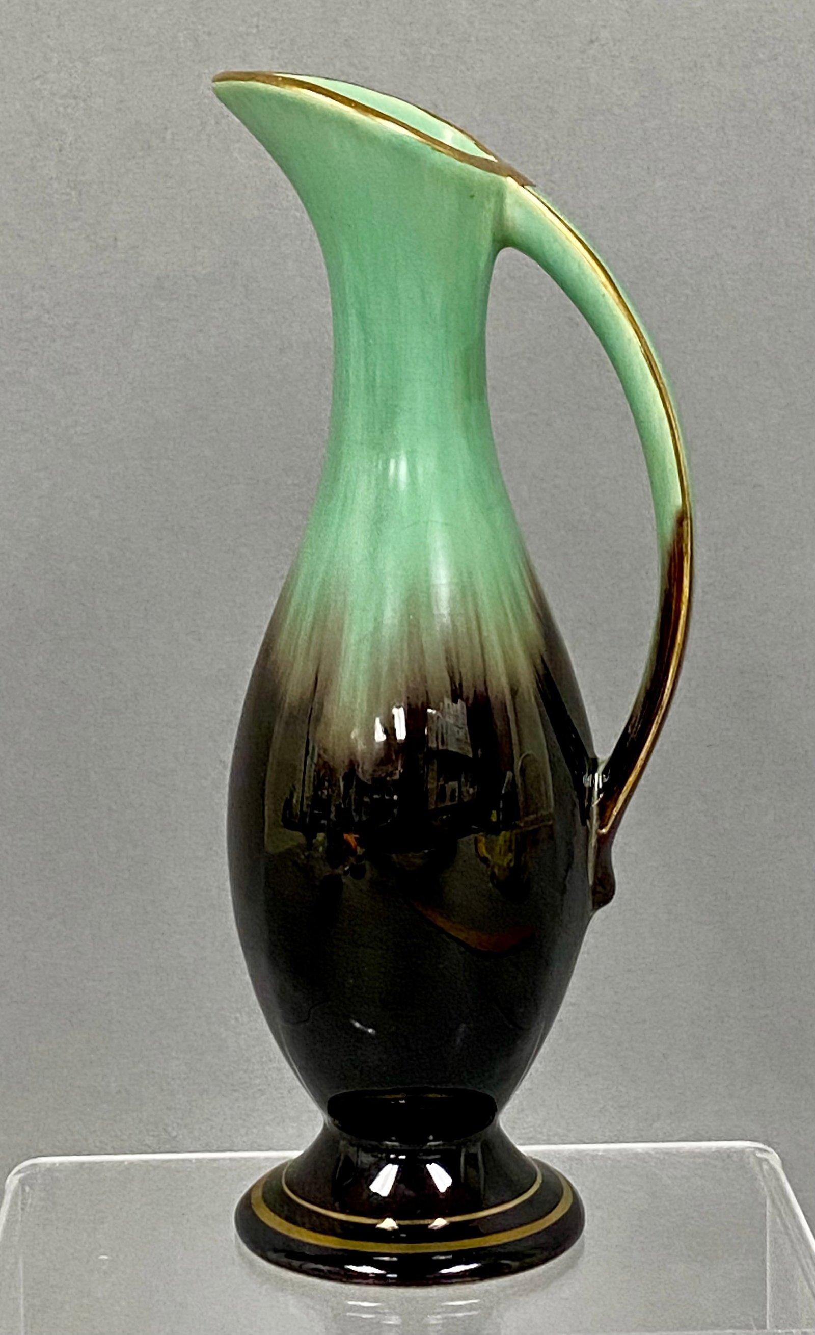 Bay Keramik West German Ewer: This West German art pottery ewer by Bay Keramik features a slender neck and a high-arching handle. The vessel is finished in a seafoam green and mahogany brown drip glaze with gold luster accents to