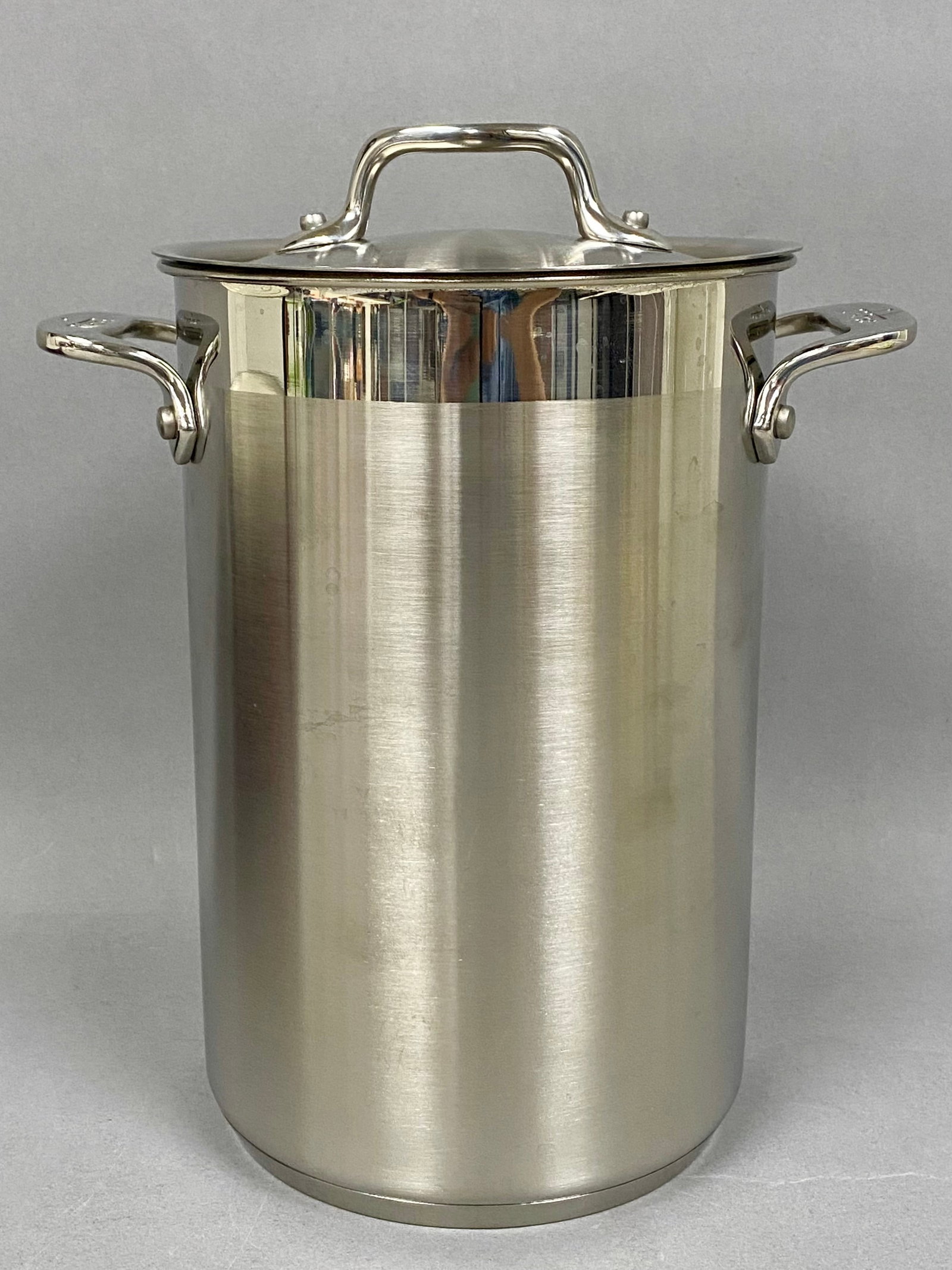 All-Clad Stainless Steel Asparagus Steamer: This All-Clad stainless steel asparagus steamer set features a tall cylindrical pot with a brushed exterior finish and polished accents. The set is constructed with professional-grade stainless steel