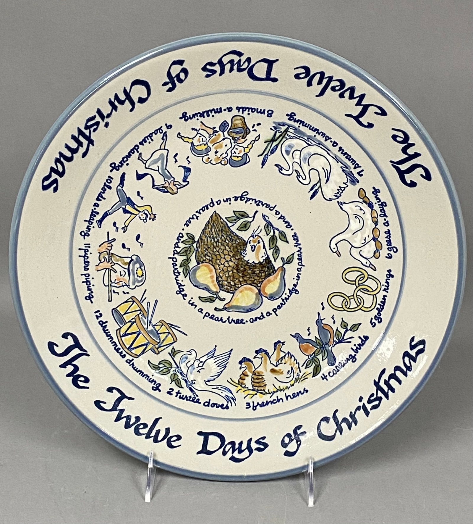 Louisville Stoneware Twelve Days Christmas Platter: A large stoneware charger by Louisville Stoneware decorated with hand-painted vignettes illustrating the Twelve Days of Christmas. The central partridge in a pear tree is encircled by eleven descripti
