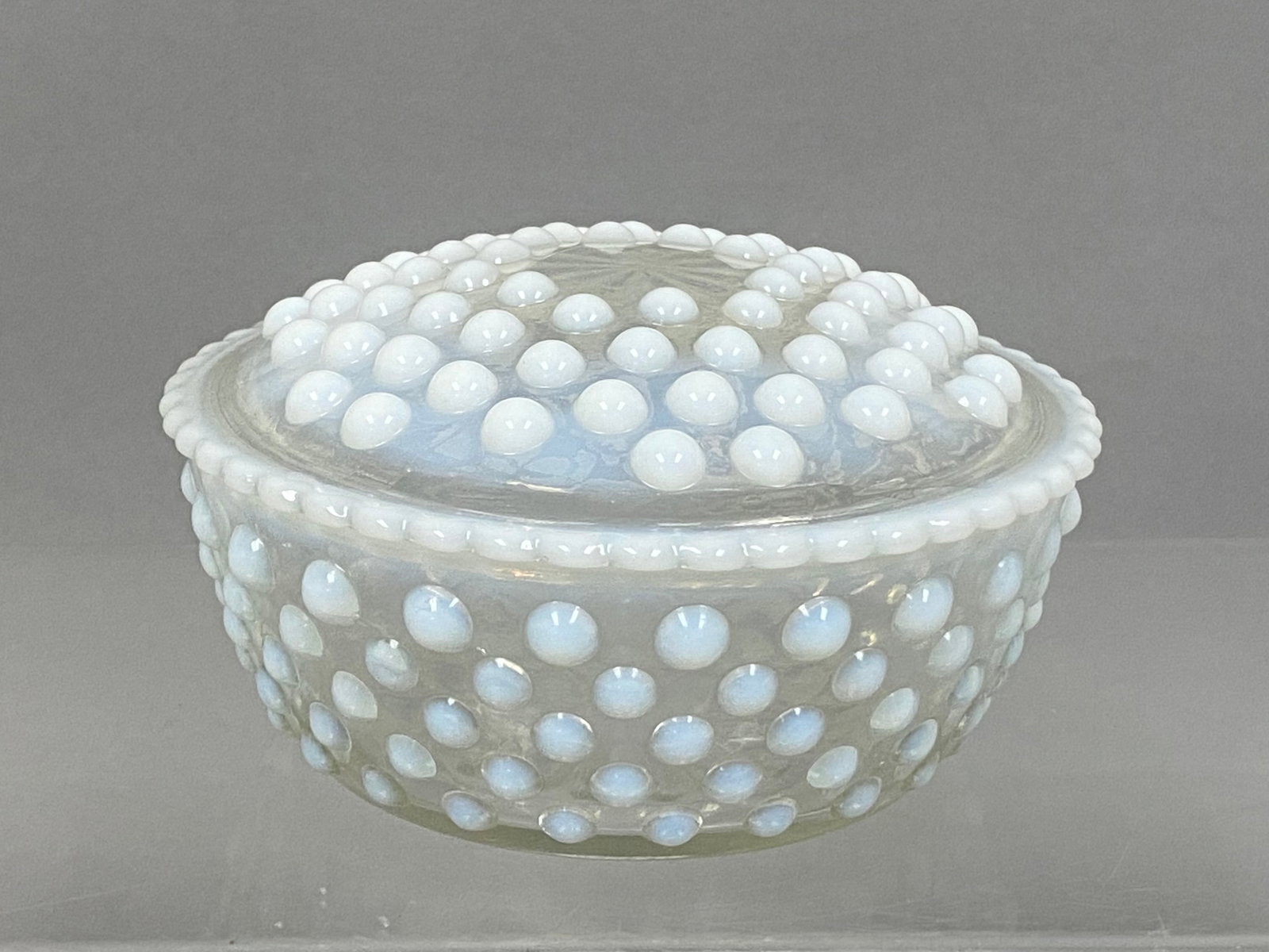 Vintage Opalescent Hobnail Lidded Dish: This vintage two-piece glass set consists of a circular bowl and a matching domed lid, both decorated with white opalescent hobnails against a clear ground. The bowl features a rayed starburst design