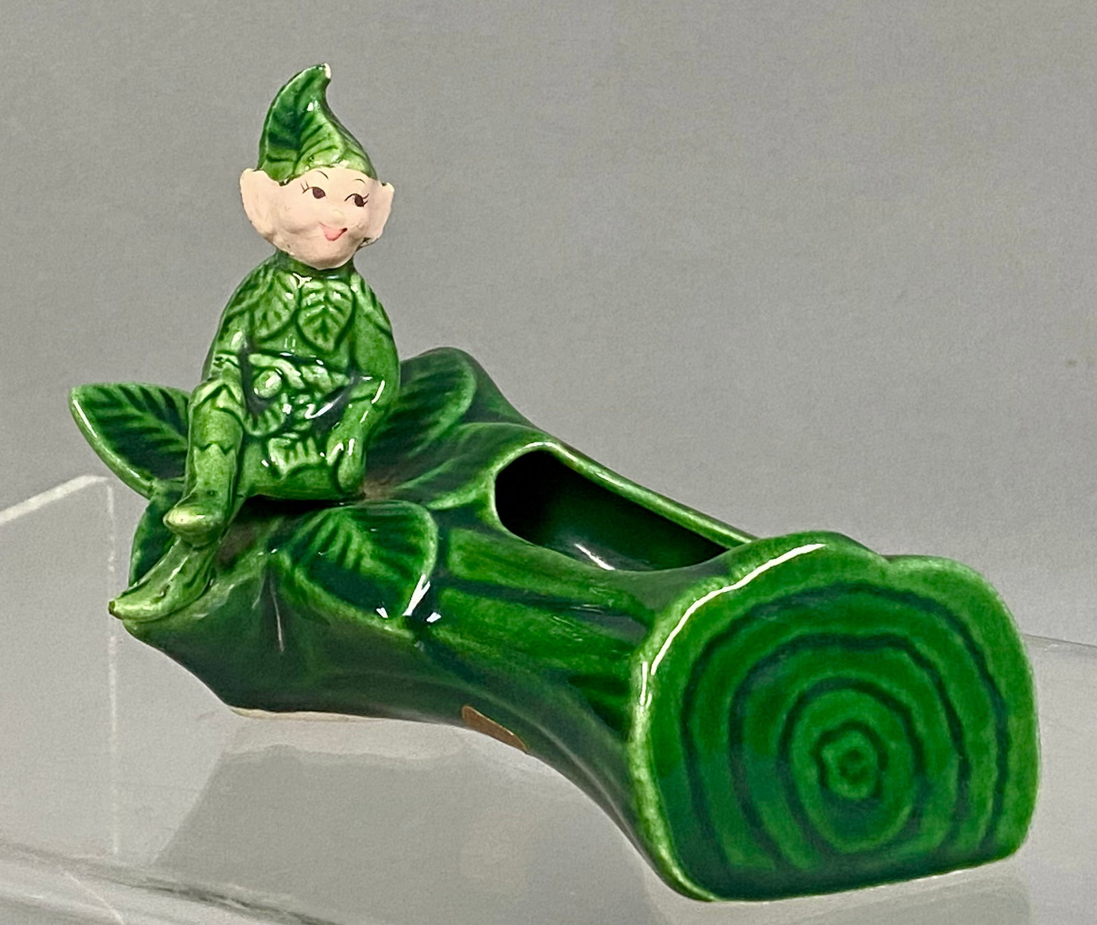 Treasure Craft Pixie Log Planter: This vintage (1950's) California pottery planter features a hand-painted pixie or sprite figure seated upon a log with leaf accents. The piece is finished in a glossy green glaze with a matte,