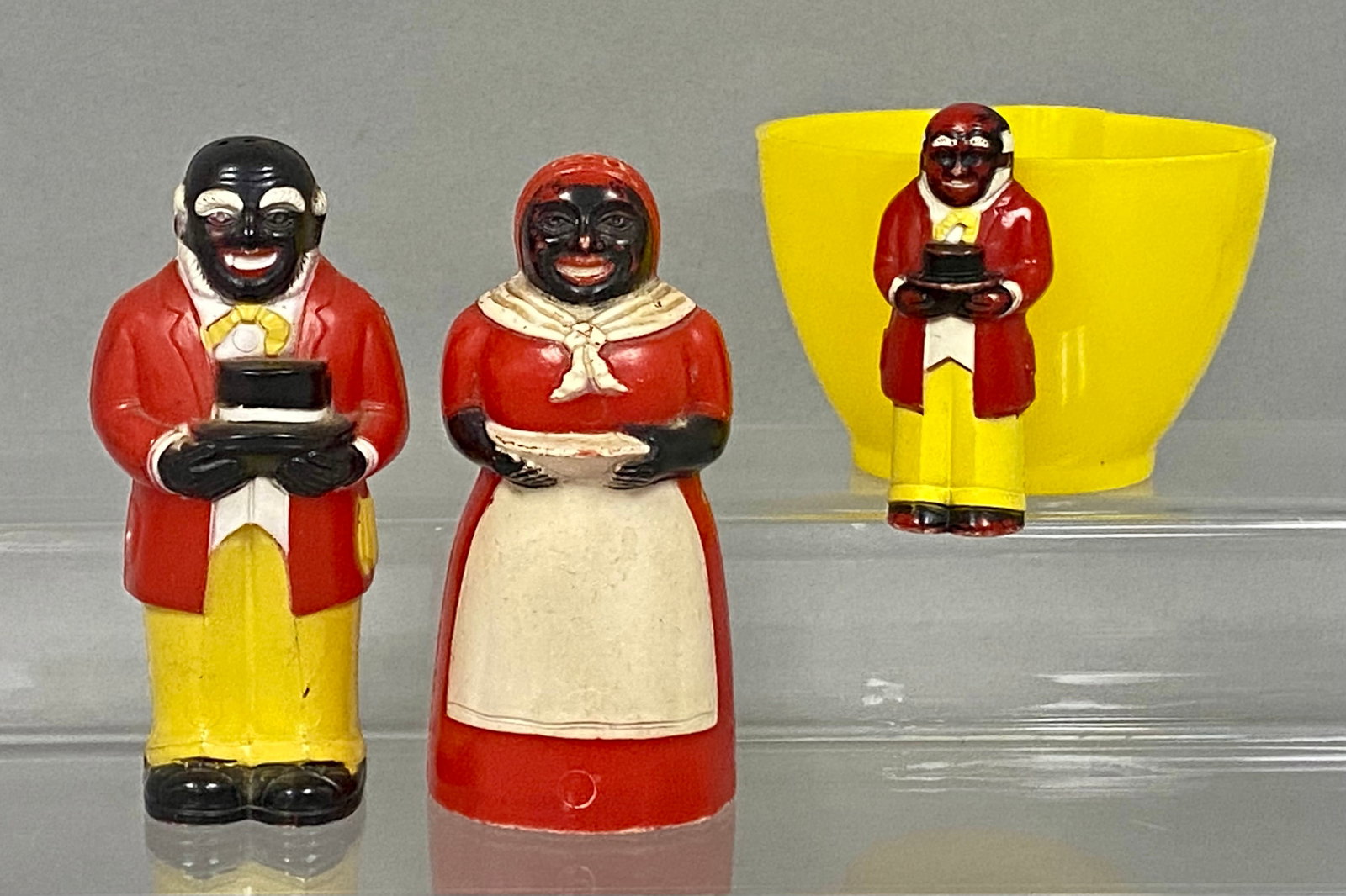 F. & F. Mold Plastic Caricature Kitchenware: A trio of mid-twentieth-century molded plastic kitchenware items produced by F. & F. Mold & Die Works, Inc. The set includes a pair of salt and pepper shakers and a yellow measuring cup with an
