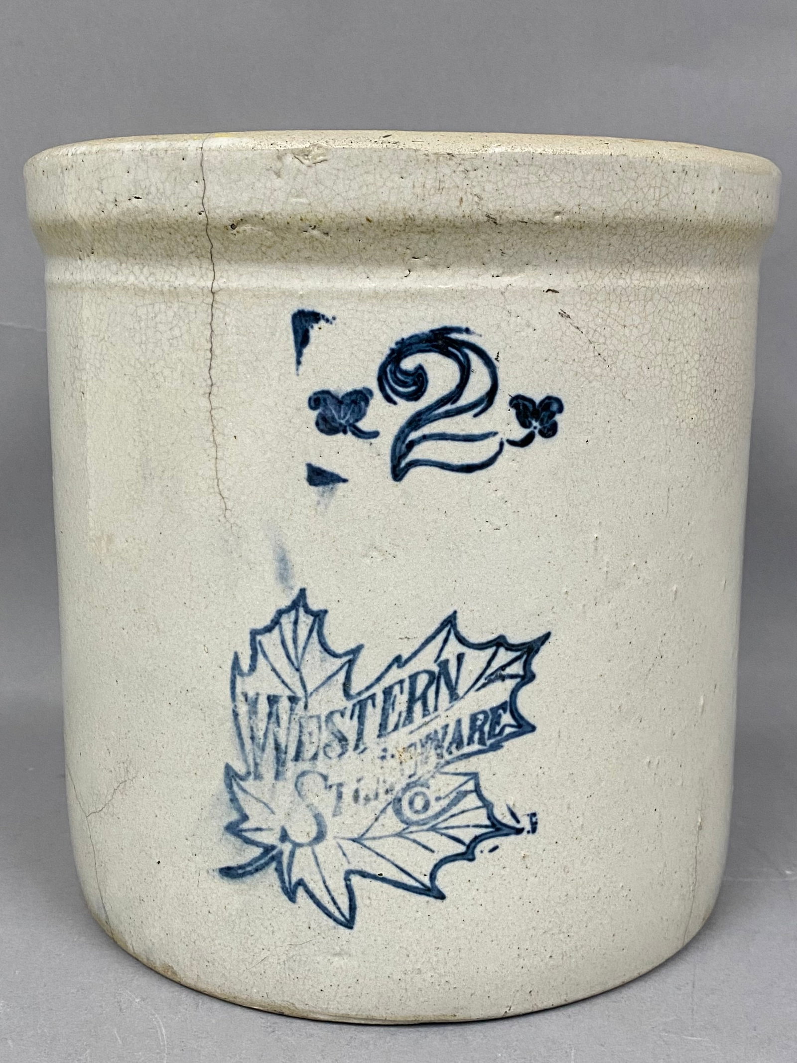 Western Stoneware Co 2-Gallon Maple Leaf Crock: An antique salt-glazed stoneware crock produced by the Western Stoneware Company of Monmouth, Illinois. The cylindrical vessel features a reinforced flared rim and is decorated with cobalt blue markin