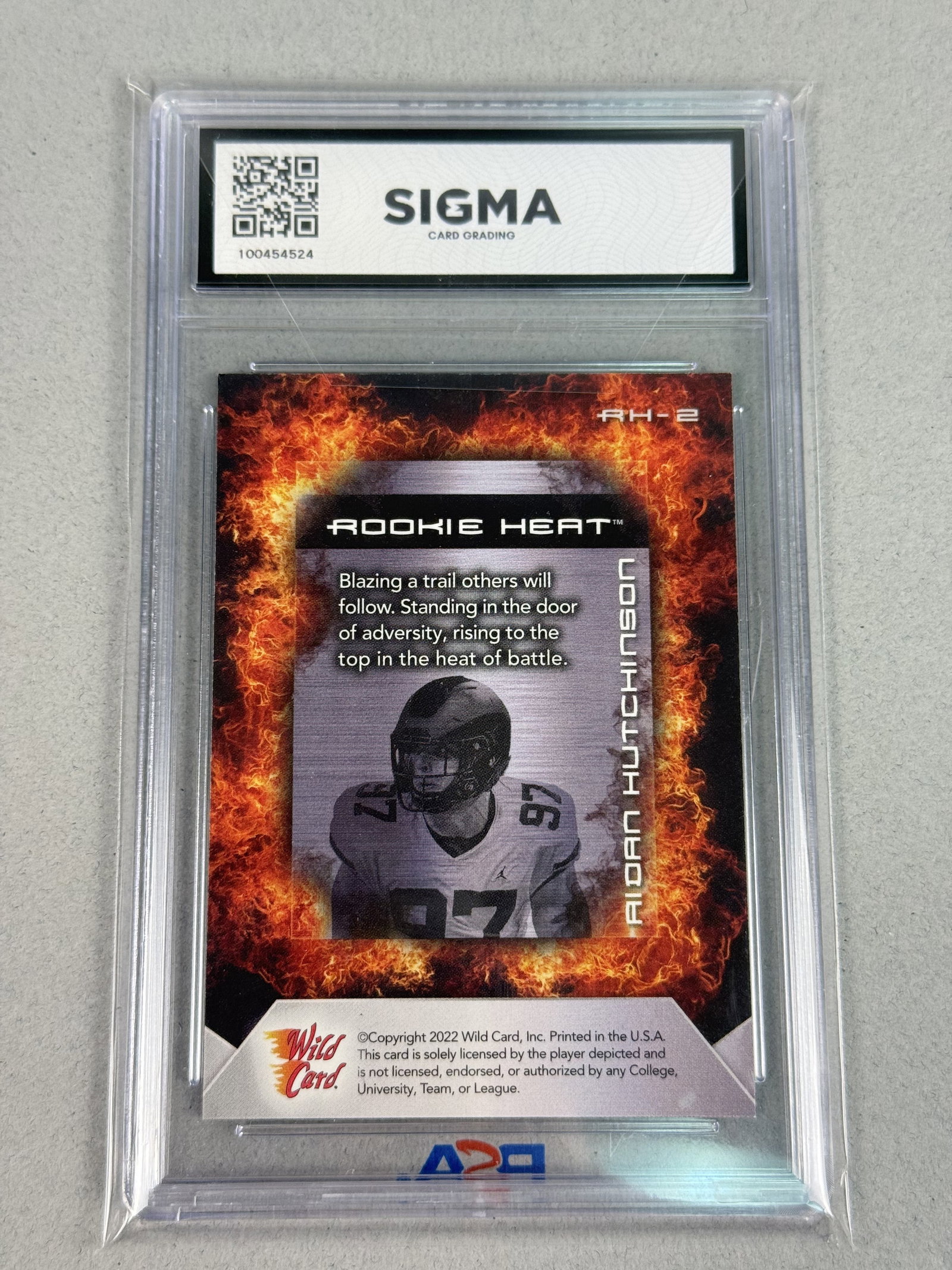 Wild Card Aidan Hutchinson Sigma 9 100454524: This 2022 Wild Card Matte American football trading card features defensive end Aidan Hutchinson. Part of the Rookie Heat insert series, the card displays a matte finish with gold foil accents on the 