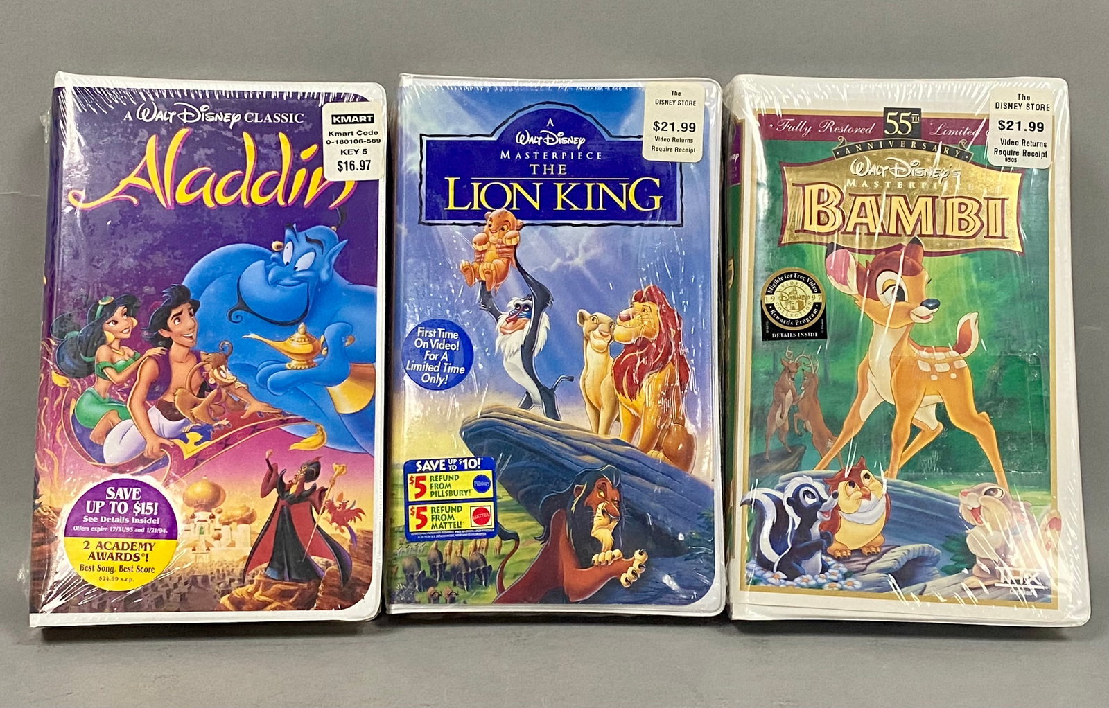 Walt Disney Sealed VHS Trio: An assortment of three factory-sealed Walt Disney home video VHS tapes in their original white plastic clamshell cases. The collection features animated feature films including the 1992 release of Ala