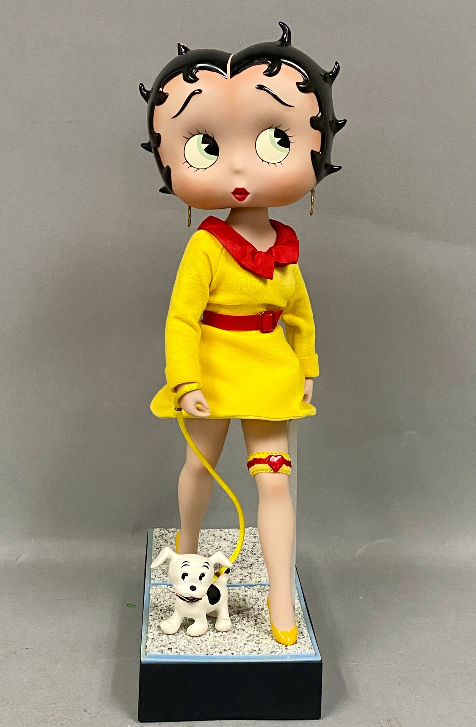 Danbury Mint Porcelain Betty Boop Walking Pudgy Figurine: This mixed-media licensed collector figurine depicts the character Betty Boop walking her dog, Pudgy. The figure features a glossy polychrome head and matte-finished porcelain limbs, dressed in a