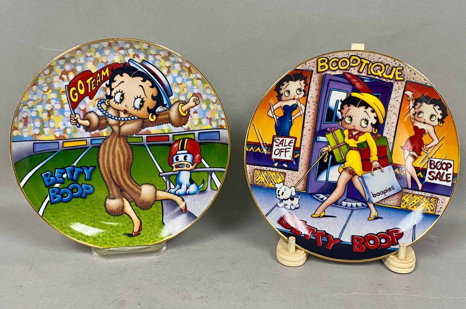 2 Danbury Mint Porcelain Betty Boop Plates: A set of two limited edition porcelain collector plates from the Betty Boop - America's Sweetheart collection by The Danbury Mint. The first plate, titled Shop Till You Drop, features a