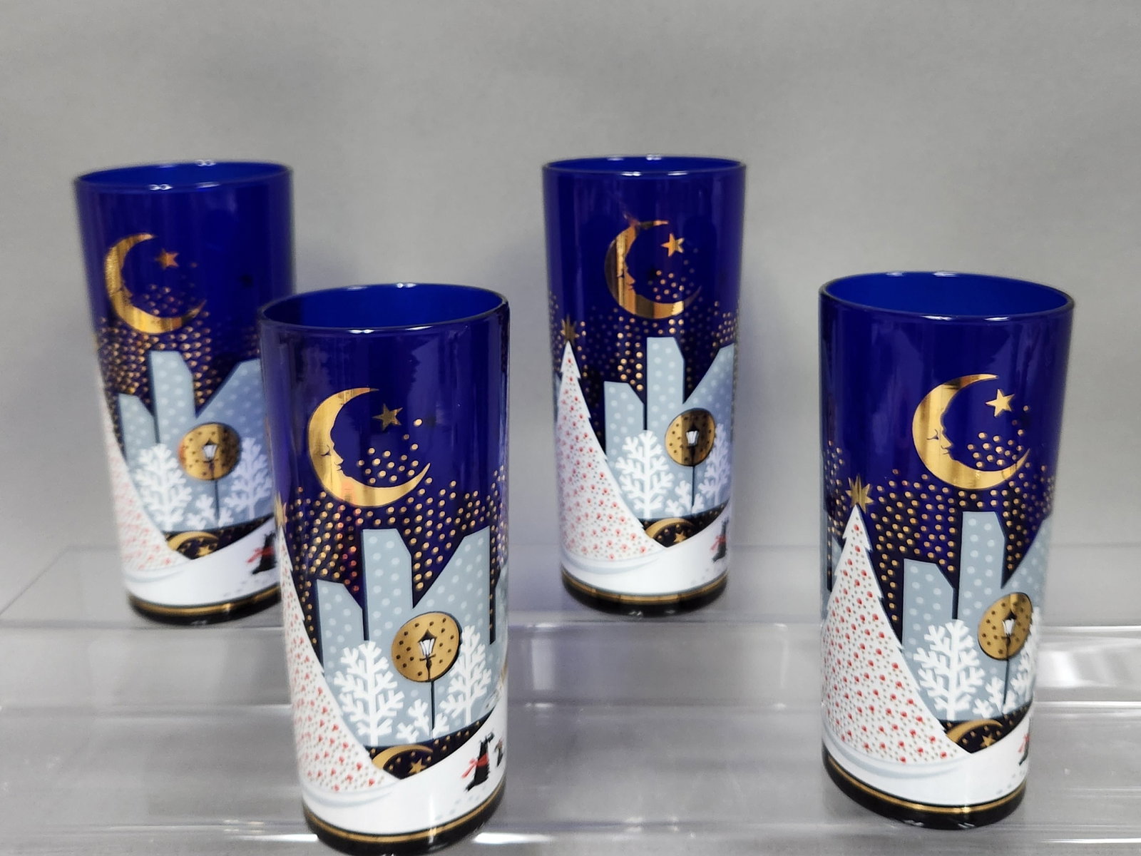Noritake 'Twas The Night Before Christmas Cobalt Tumblers: A set of four cobalt blue glass hiball tumblers in the 'Twas the Night Before Christmas pattern by Noritake. Each vessel features an extensive wrap-around enameled and gold-toned decoration depicting