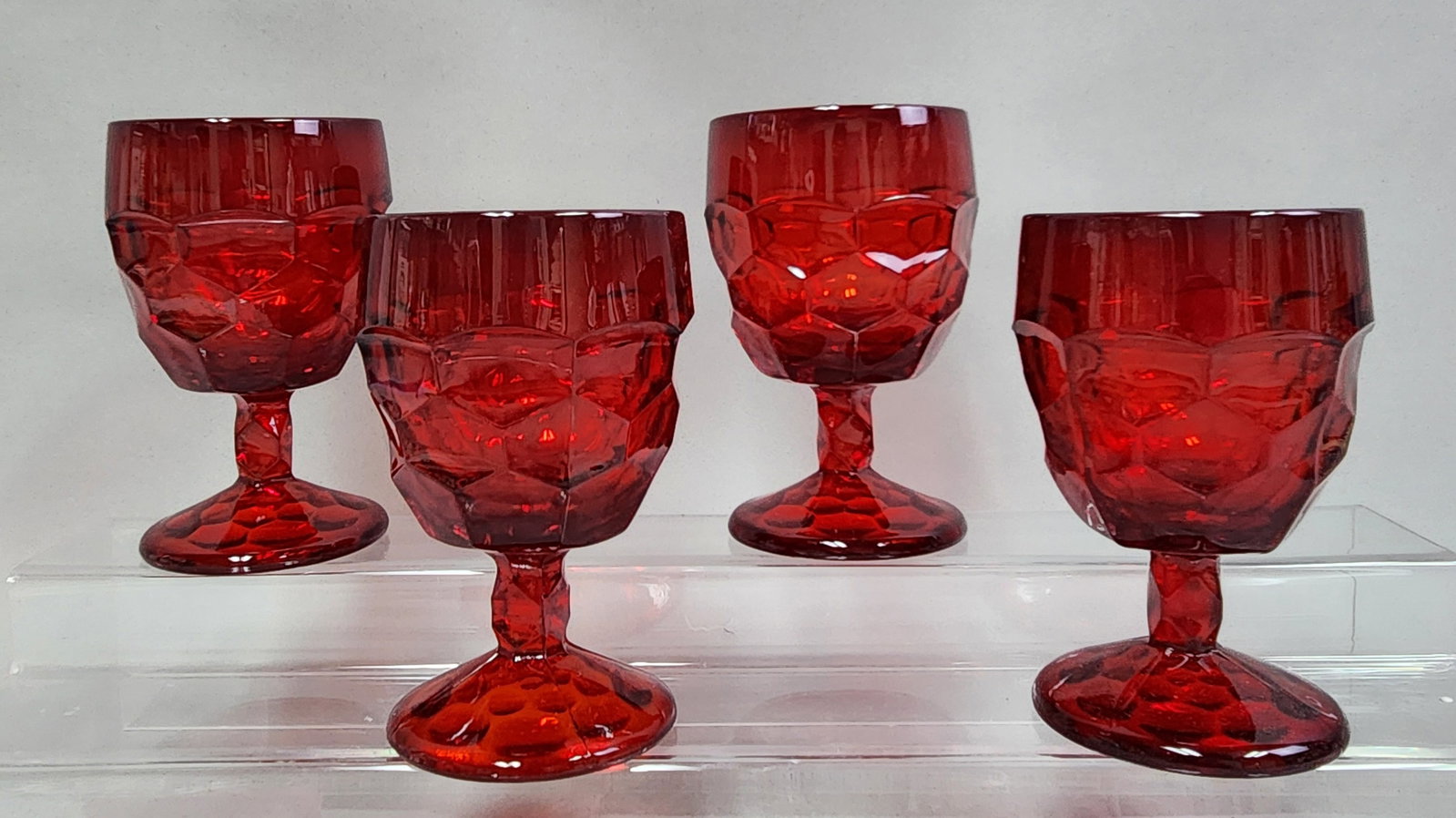 Viking Georgian Ruby Red Glass Goblets: A set of four matching ruby red pressed glass goblets by Viking. Height: 5.75 inches The set is in excellent vintage condition with no visible chips, cracks, or repairs. All faceted edges are smooth