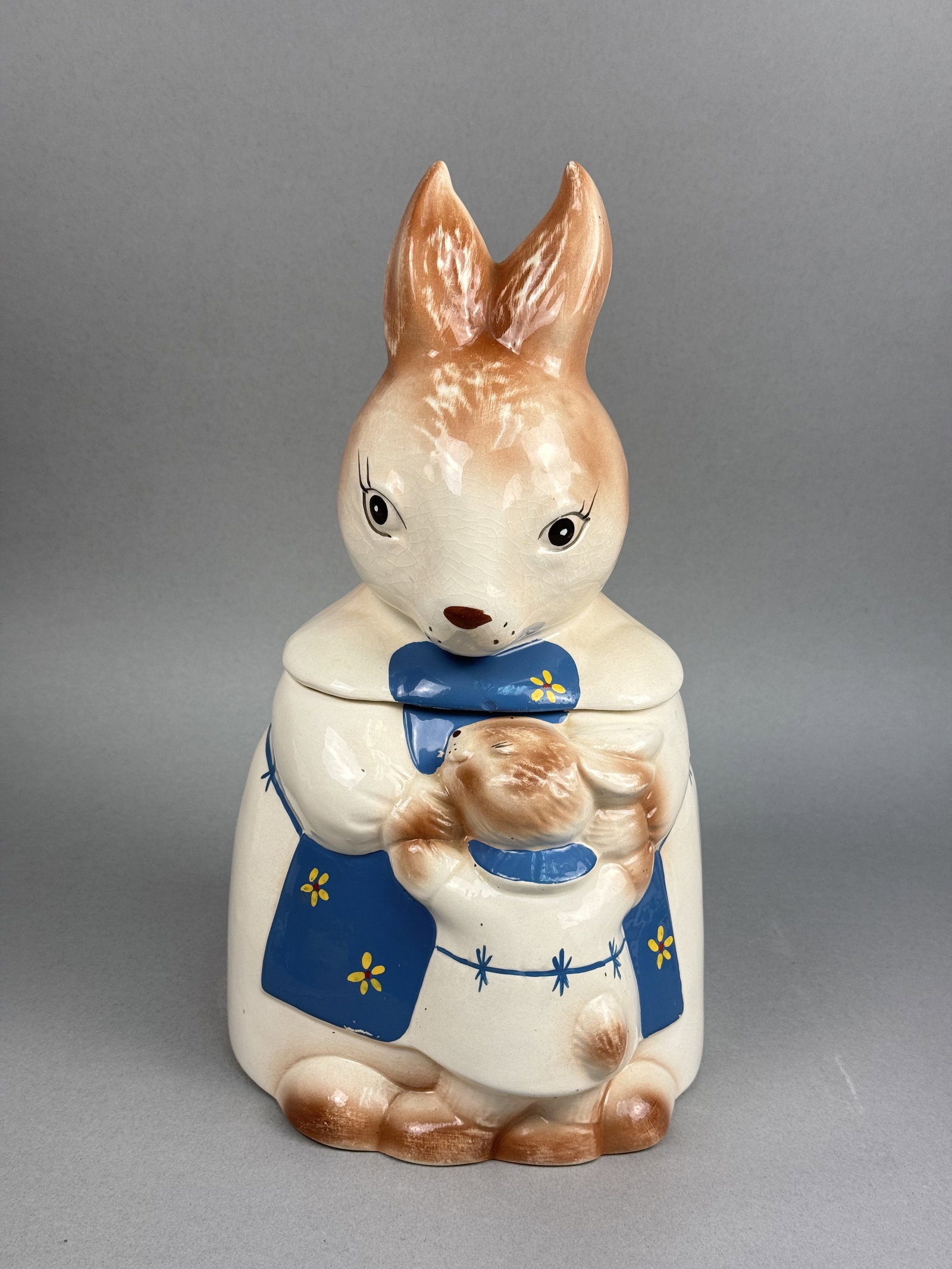 Earthenware Mother & Baby Rabbit Cookie Jar: A mid-century earthenware figural cookie jar designed in the form of a mother rabbit holding a baby rabbit. The interior is finished with a cream-colored glaze, and the underside of the base is
