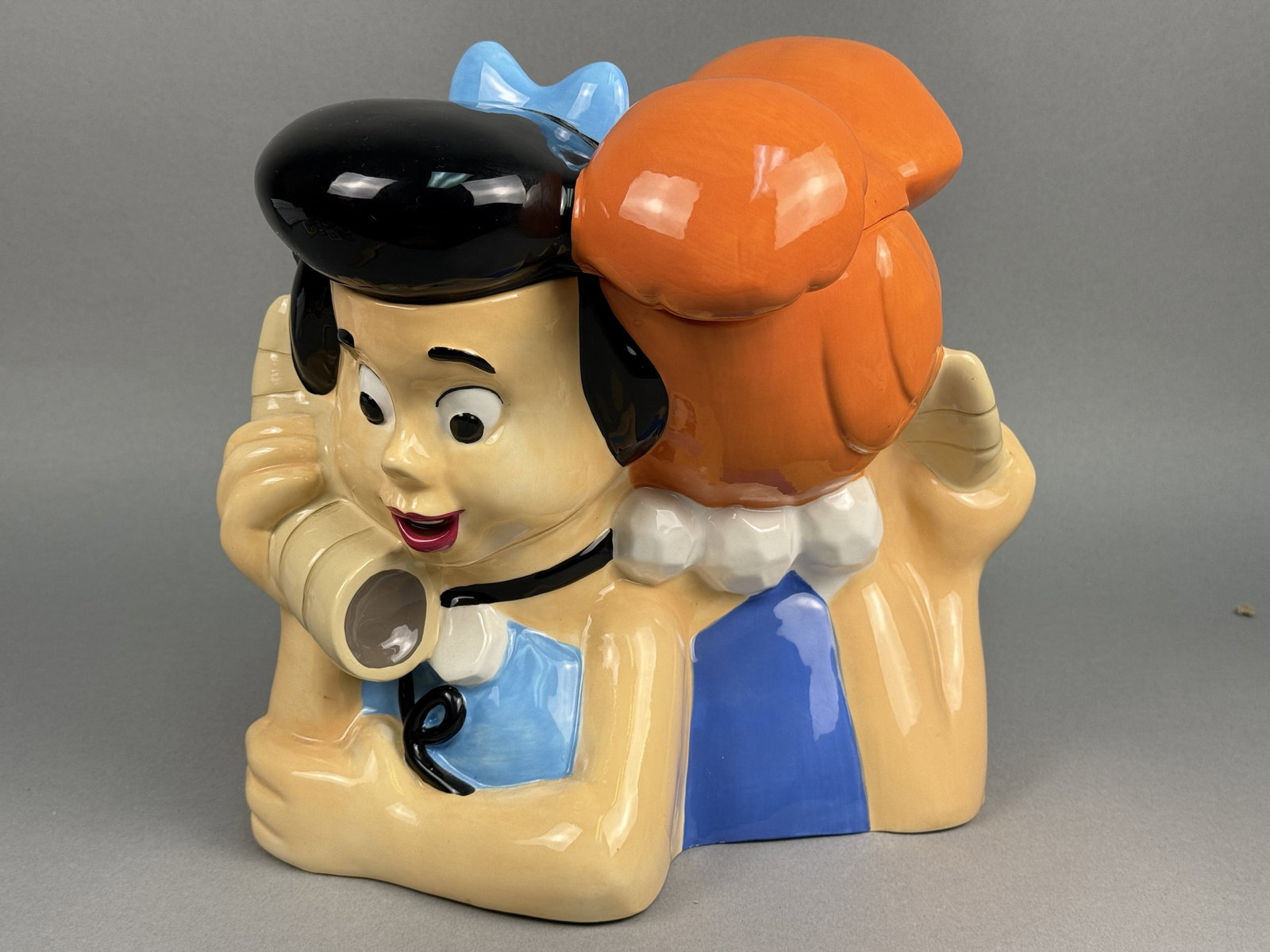 Warner Bros. Ceramic Wilma & Betty Cookie Jar: This hand-painted glazed ceramic cookie jar features the crossover characters Wilma Flintstone and Betty Rubble from the Hanna-Barbera animated series. The underside of the jar bears a black rectangul