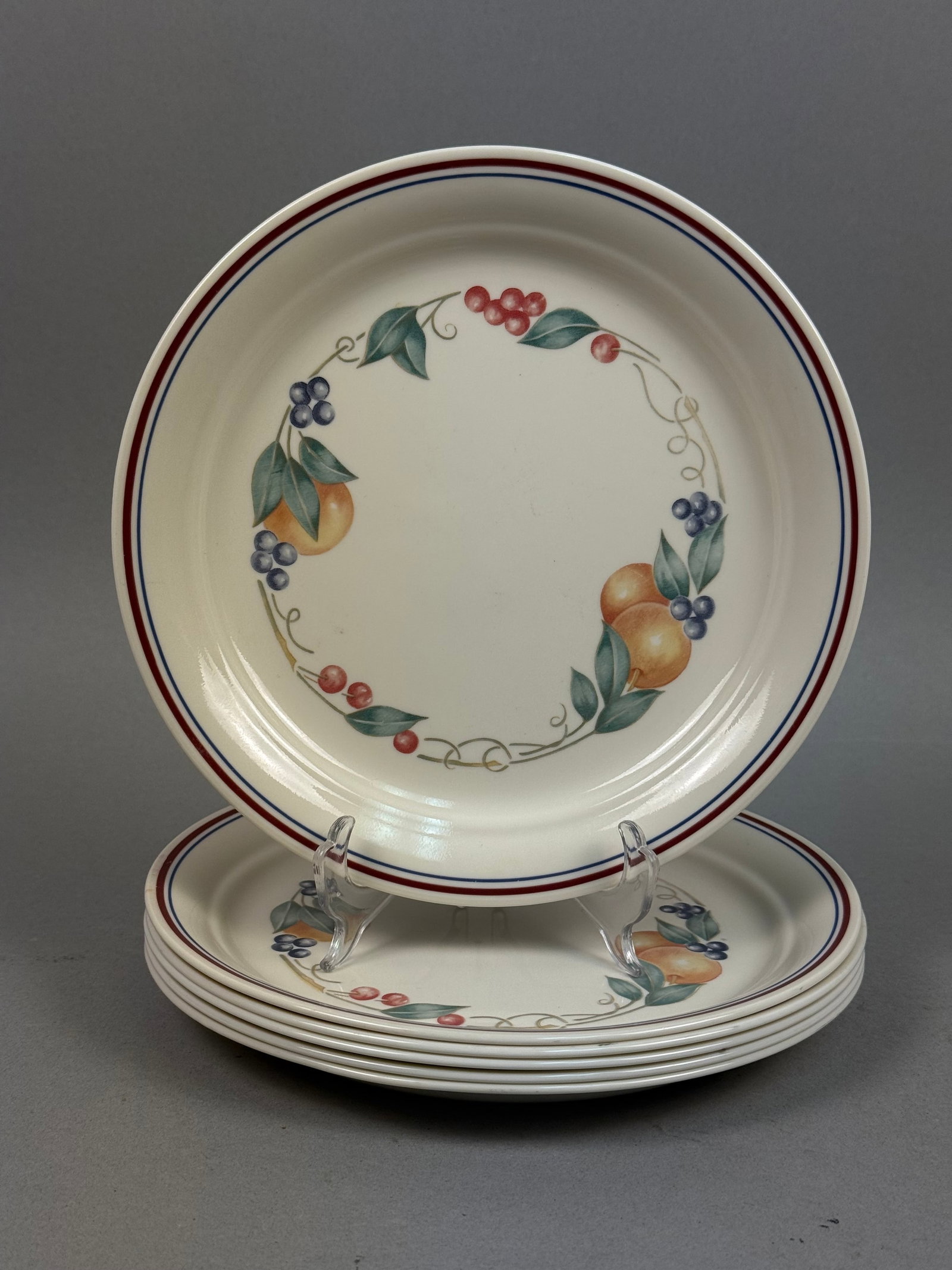 Corelle Abundance Vitrelle Dinner Plates: A set of six circular dinner plates crafted from Vitrelle glass laminate. The plates feature the Abundance pattern, characterized by a central fruit wreath design. The outer rim is detailed with two c