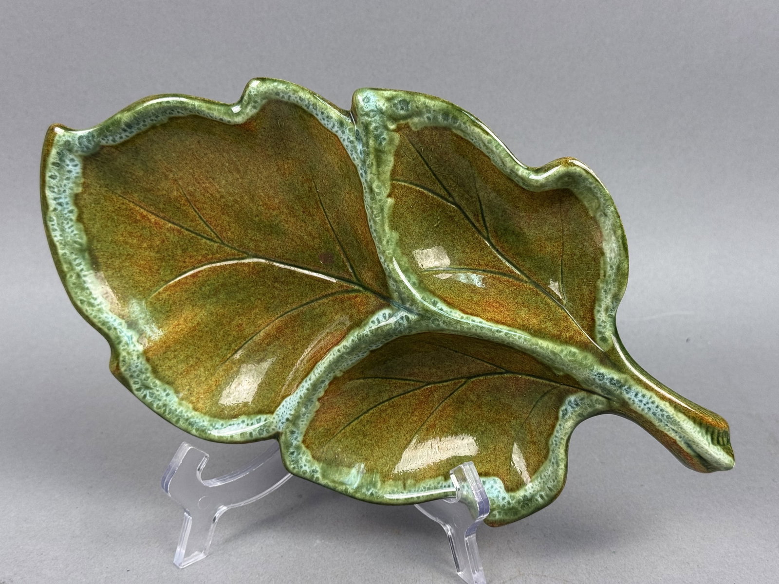 Ceramic Three-Section Glazed Leaf Dish: A mid-century ceramic relish or nut dish formed as a large stylized leaf with a short, curved stem handle. The interior surface is divided into three functional compartments by relief-molded veining. 