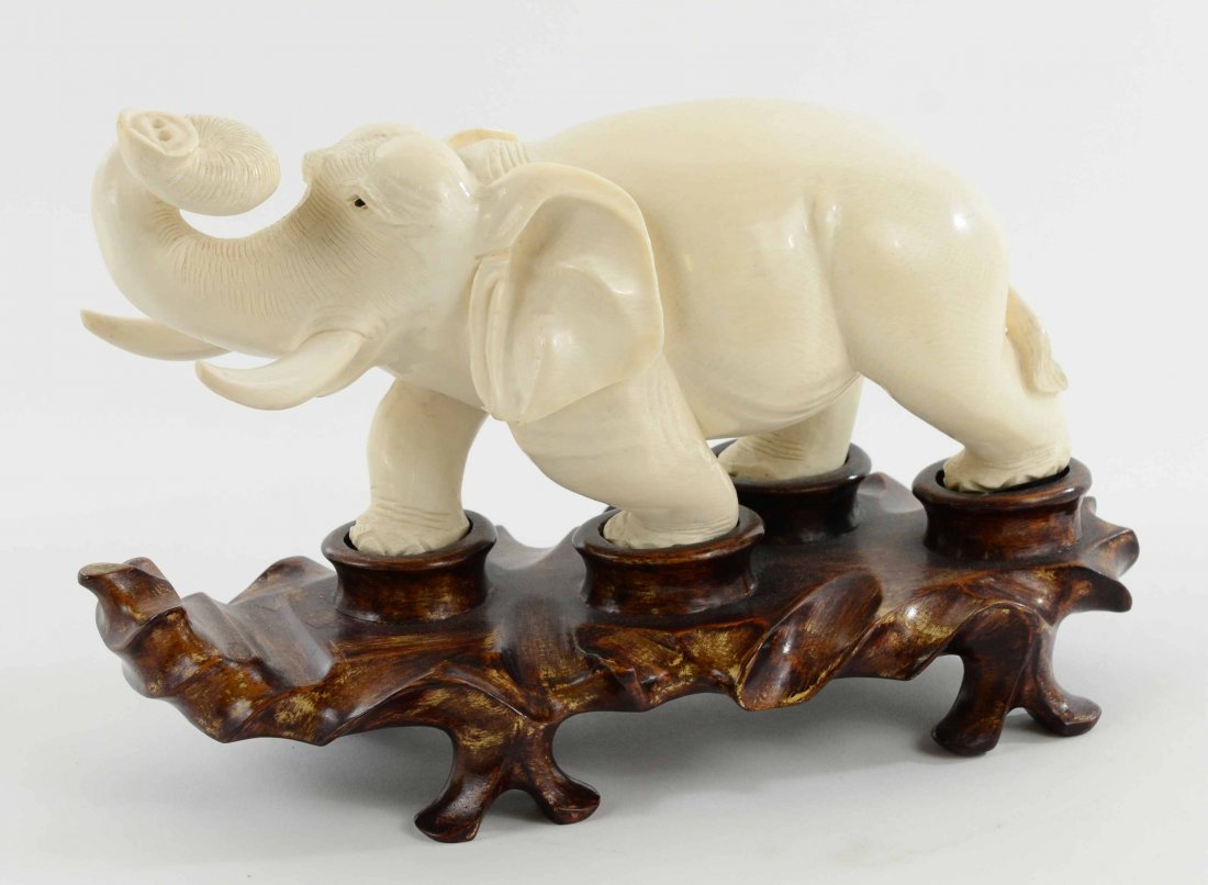 Antique Solid Carved Ivory Elephant on Carved Wood Base: This is an Antique Carved Ivory Elephant upon a Wooden Base, from Asia in the 1920's. This magnificent piece is finely carved from one piece and is adhered to a carved wooden base. The elephant has wo
