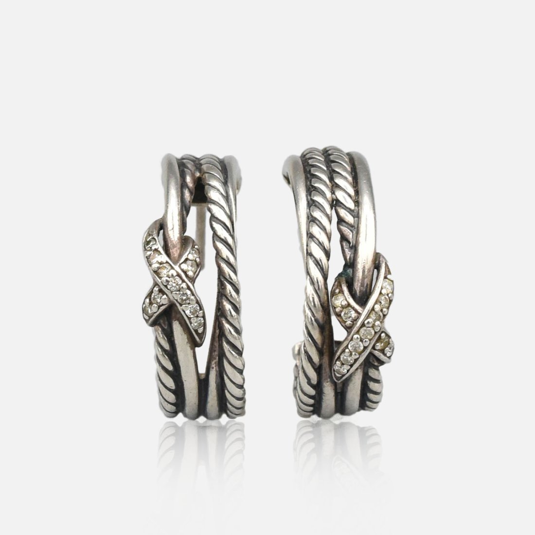 David Yurman Crossover Sterling Silver and Diamond Hoop Pierced Earrings: Excellent, however needs cleaning. Combined weight approx. 8.1 Grams, Marked "D Y 925". Each measures approx 21mm x 9mm. Features round full cut diamonds.
