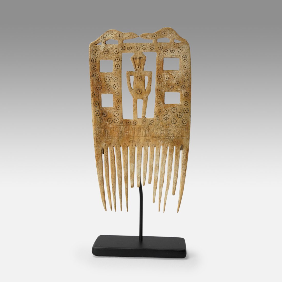 Antique 17th-18thC Chinook or Quinault Native American Indian Carved Bone Comb: Carved and pierced from a single piece, showing a central standing human figure, with open block "windows" to either side, a pair of confronting otters overhead, a band of incised stripes over the tin