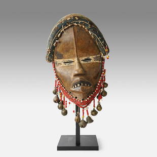 Antique African Dan Mano Tribal Mask w/Trade Beads and Bells Ivory Coast: White band across slit eyes; open mouth, inset metal teeth; fiber headgear, face trimmed in antique trade beads, dangling cast bronze bells. Ex-Henri Kremer, Ex-Marc and Denise Ginzberg NY,