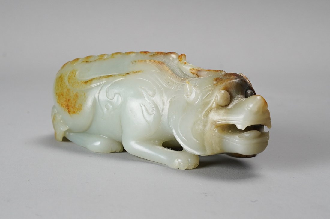 Antique Chinese Qing Celadon and Russet Jade Carved Buddhist Lion Figurine: Ca. 19th to early 20thC. Good condition overall, this creature features a russet colored spine and high points. The only condition issue of note is a tiny nick on one tooth. Weighs approx. 660 grams. 