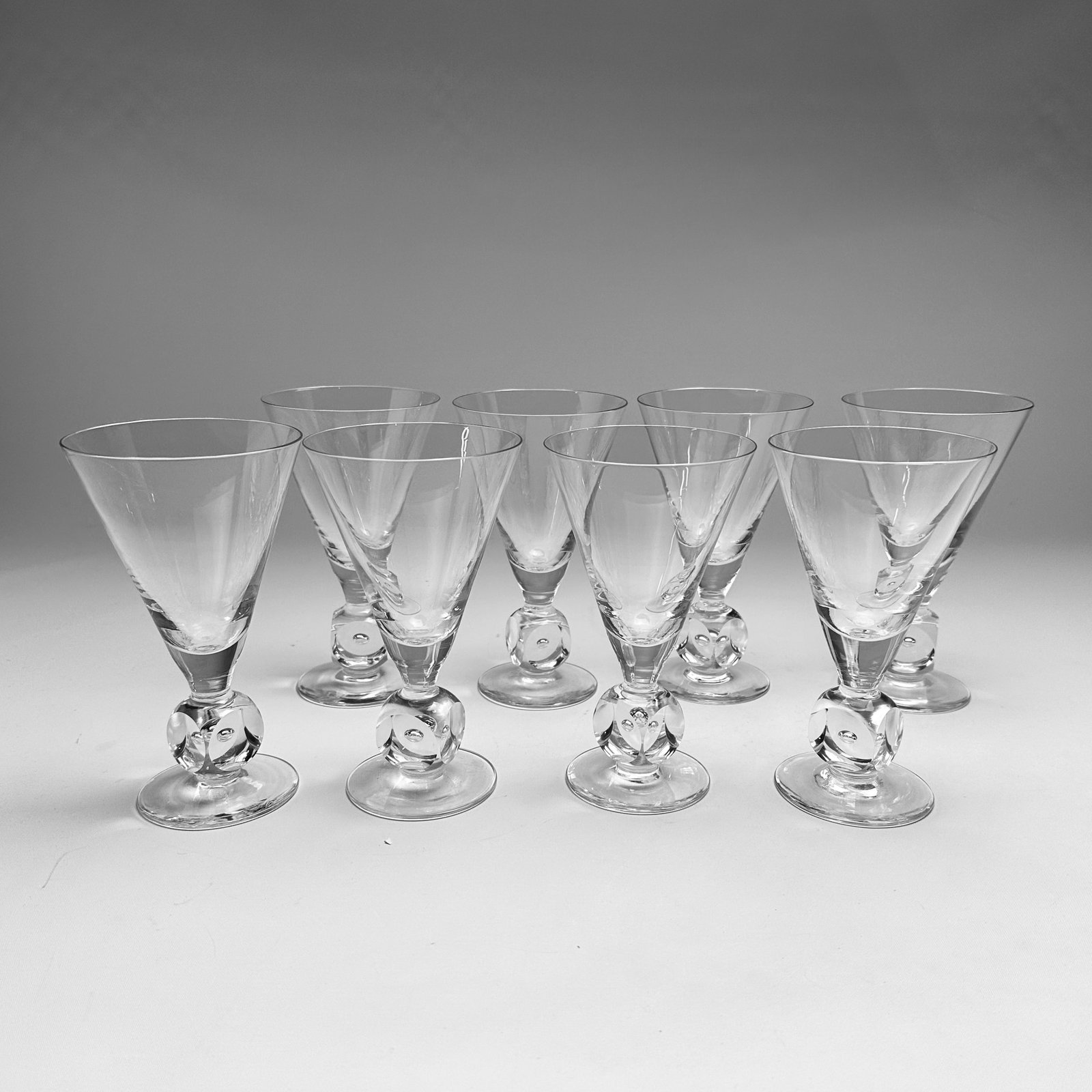 Eight Square Bubble Stem Tall Martini Glasses Manner of Kosta Boda: Ca. mid to third quarter 20thC. Apparently unsigned, however these are matches to KB square bubble stems. All glasses are in very good condition, with no chips along rims.