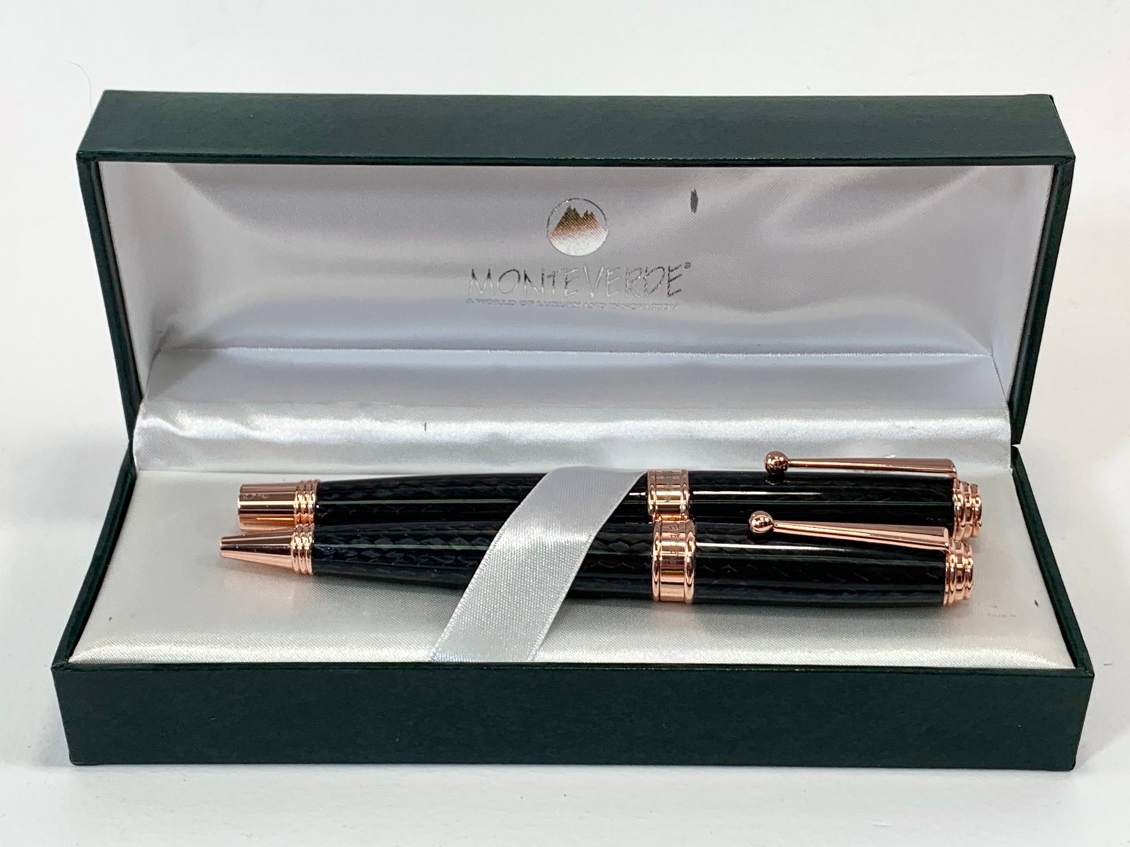 Monteverde USA Invincia Deluxe Black Weave and Rose Gold Fountain and Ballpoint Pen Set w/Box: Excellent single use condition, with no defects. Approx. 5 1/2". Glossy finish throughout. Box may show moderate shelf wear, and may include ink stains. Please enlarge pictures to clearly understand b